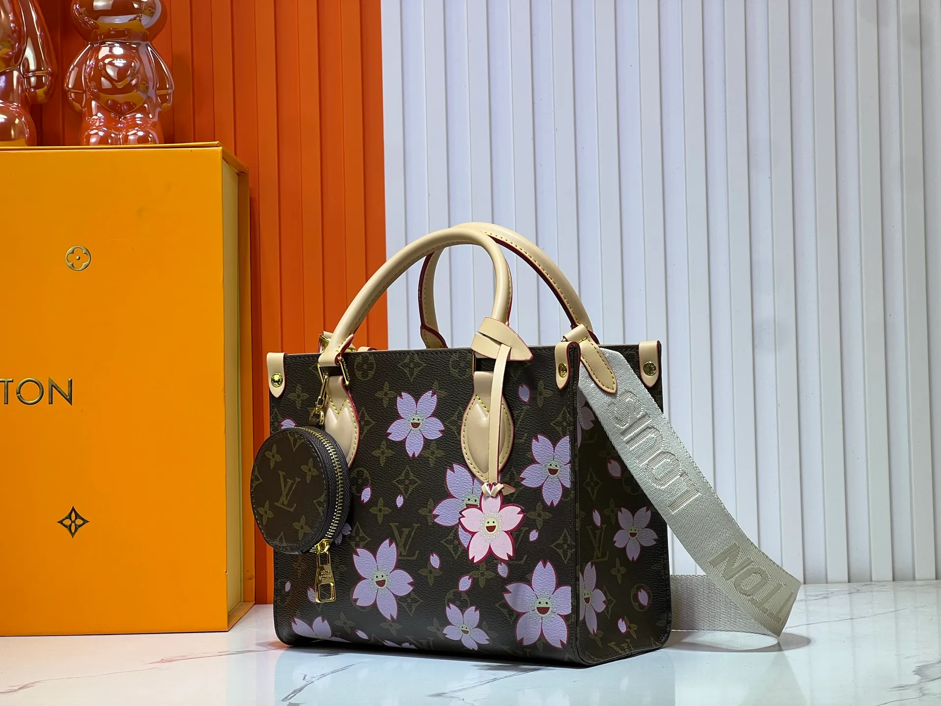 Batch 320💰M45659 M46373🔥Lv&Takashi Murakami🐼Sakura🌸OnTheGo small new version The legendary ONTHEGO handbag: always able to meet your various needs for handbags. It has a large capacity but is not bulky. It is stiff and soft to the touch, making it suitable for home and travel. Tighten the side ties and it instantly transforms into a stylish urban handbag. Loosen the straps and it transforms into a chic and practical handbag. The slender leather handle can be carried over the shoulder or between the arms. The model shown here is made of Damier Azur canvas. Size: 25x11x19cm