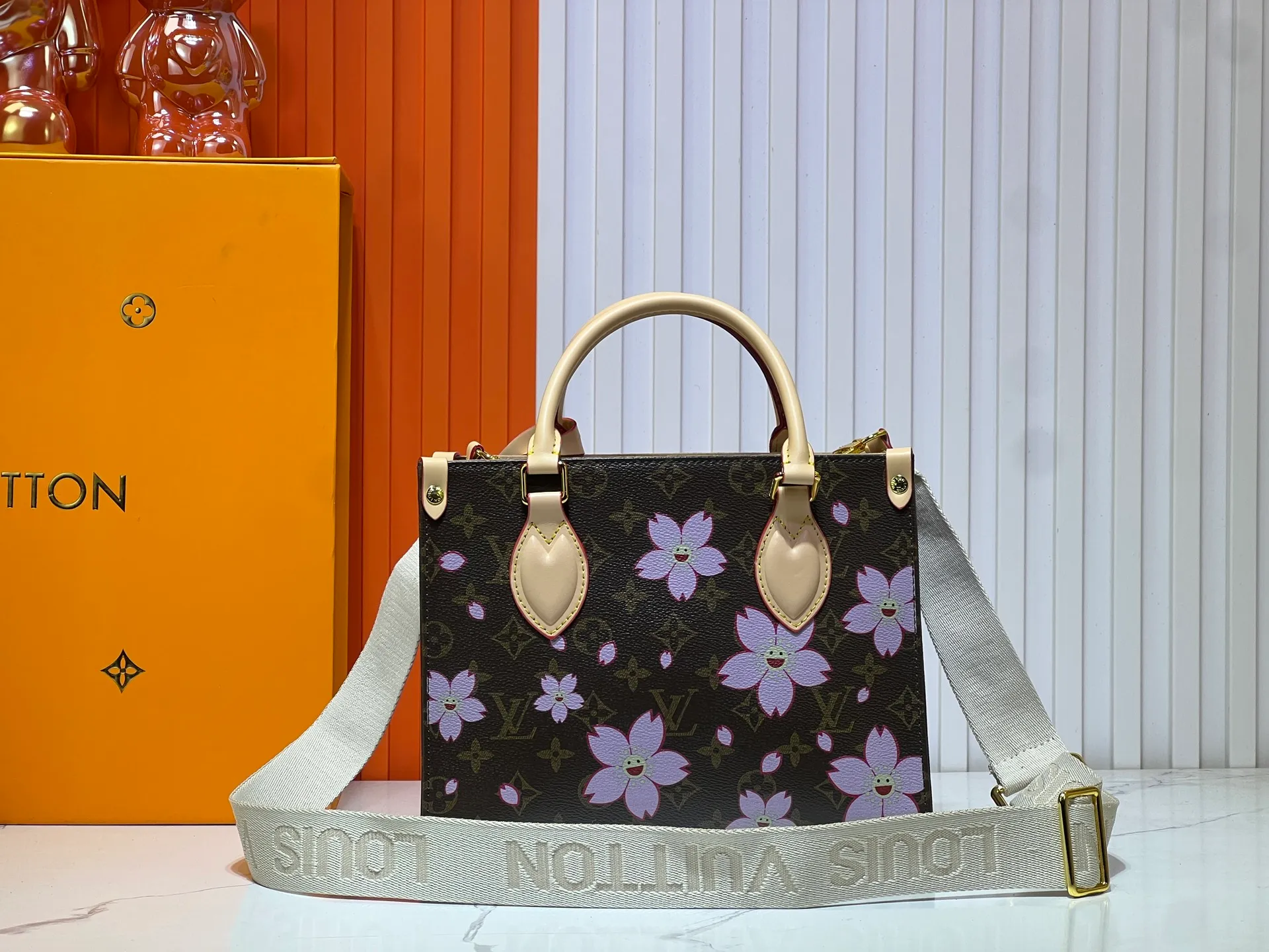 Batch 320💰M45659 M46373🔥Lv&Takashi Murakami🐼Sakura🌸OnTheGo small new version The legendary ONTHEGO handbag: always able to meet your various needs for handbags. It has a large capacity but is not bulky. It is stiff and soft to the touch, making it suitable for home and travel. Tighten the side ties and it instantly transforms into a stylish urban handbag. Loosen the straps and it transforms into a chic and practical handbag. The slender leather handle can be carried over the shoulder or between the arms. The model shown here is made of Damier Azur canvas. Size: 25x11x19cm