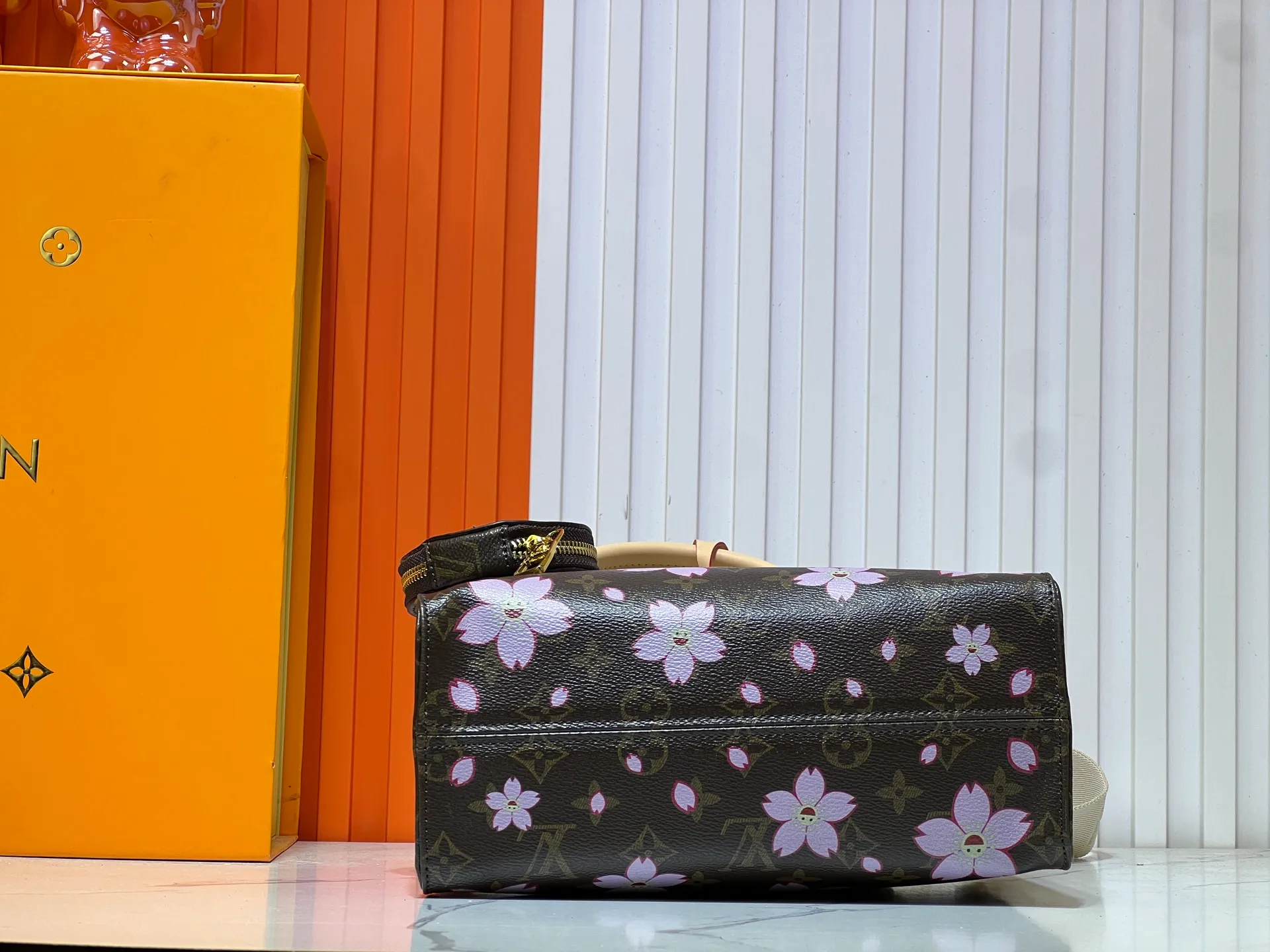 Batch 320💰M45659 M46373🔥Lv&Takashi Murakami🐼Sakura🌸OnTheGo small new version The legendary ONTHEGO handbag: always able to meet your various needs for handbags. It has a large capacity but is not bulky. It is stiff and soft to the touch, making it suitable for home and travel. Tighten the side ties and it instantly transforms into a stylish urban handbag. Loosen the straps and it transforms into a chic and practical handbag. The slender leather handle can be carried over the shoulder or between the arms. The model shown here is made of Damier Azur canvas. Size: 25x11x19cm