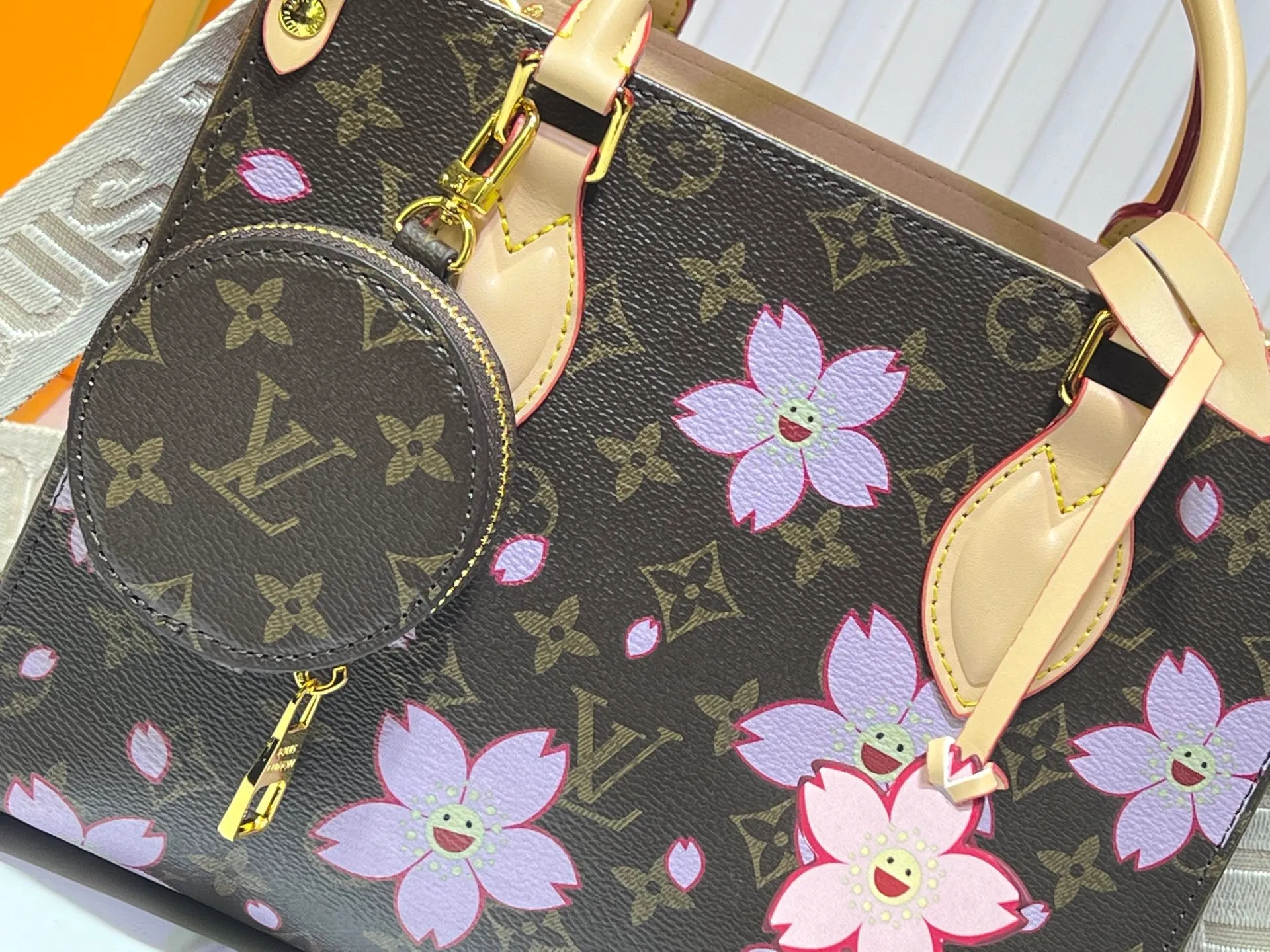Batch 320💰M45659 M46373🔥Lv&Takashi Murakami🐼Sakura🌸OnTheGo small new version The legendary ONTHEGO handbag: always able to meet your various needs for handbags. It has a large capacity but is not bulky. It is stiff and soft to the touch, making it suitable for home and travel. Tighten the side ties and it instantly transforms into a stylish urban handbag. Loosen the straps and it transforms into a chic and practical handbag. The slender leather handle can be carried over the shoulder or between the arms. The model shown here is made of Damier Azur canvas. Size: 25x11x19cm