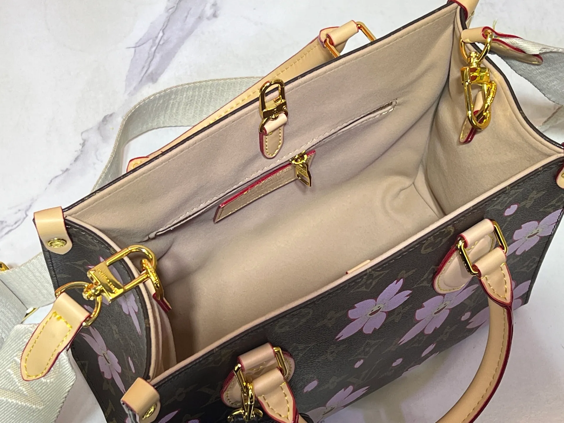 Batch 320💰M45659 M46373🔥Lv&Takashi Murakami🐼Sakura🌸OnTheGo small new version The legendary ONTHEGO handbag: always able to meet your various needs for handbags. It has a large capacity but is not bulky. It is stiff and soft to the touch, making it suitable for home and travel. Tighten the side ties and it instantly transforms into a stylish urban handbag. Loosen the straps and it transforms into a chic and practical handbag. The slender leather handle can be carried over the shoulder or between the arms. The model shown here is made of Damier Azur canvas. Size: 25x11x19cm