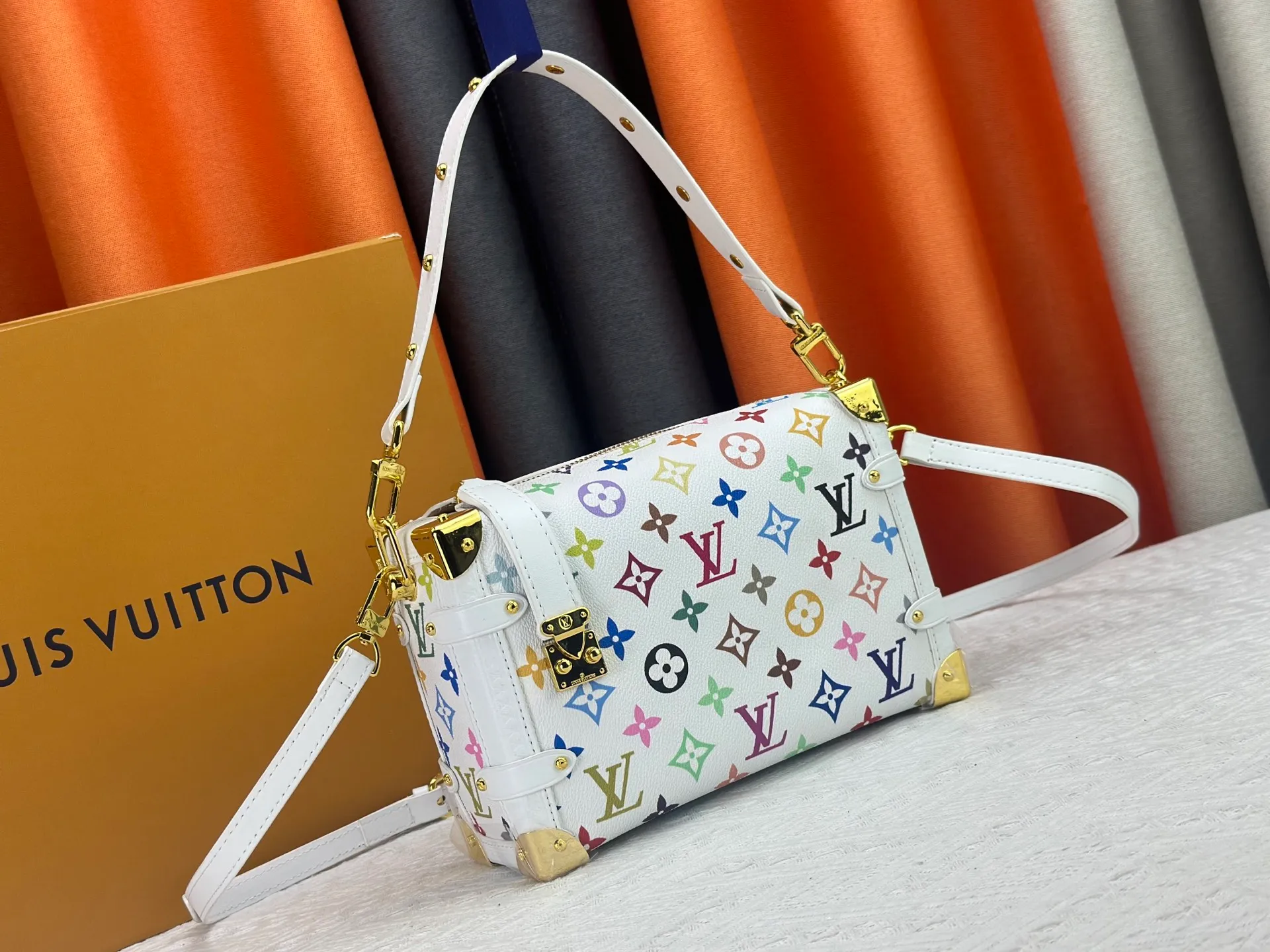 P280 M14046 M46358 Black Tricolor White Tricolor This Side Trunk medium handbag uses a humorous Monogram pattern to express the smart style of the Louis Vuitton × Murakami reissue series. It is made of soft cow leather with reinforced metal corners and the iconic S-lock lock, which can easily accommodate daily needs. The square shape is a nod to the brand's classic luggage, and the removable studded handle and shoulder strap allow for flexible carrying. Size: 23.5x16x8.5cm