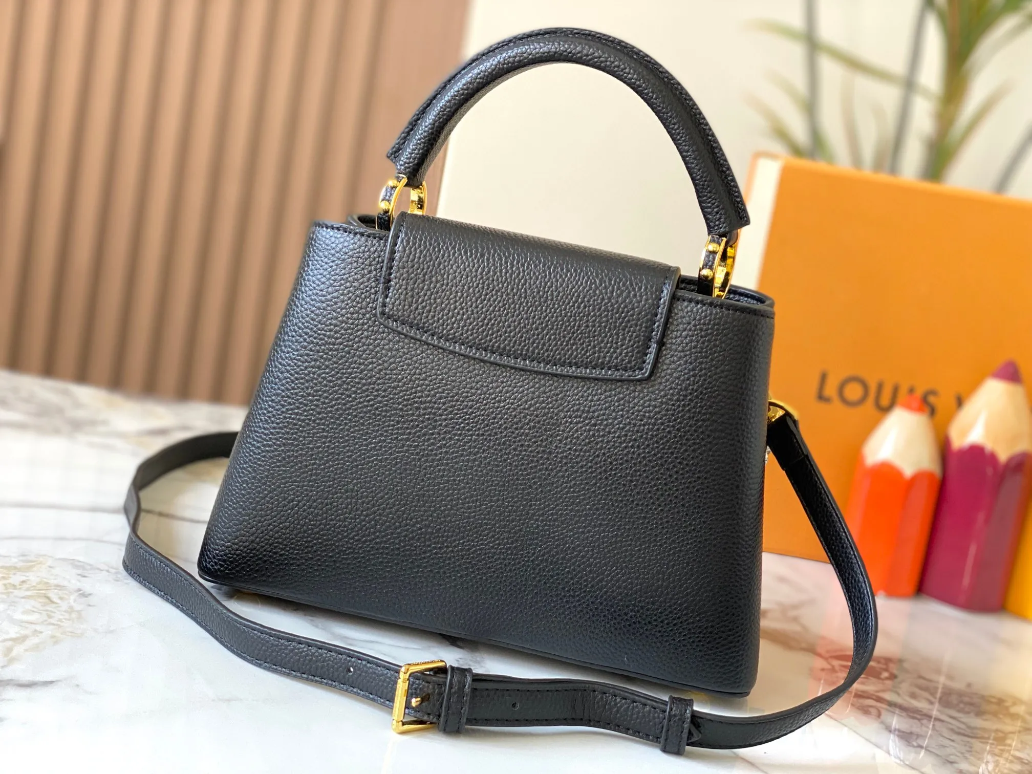 P500 [Guangzhou top quality original version] M26532 black gold. This modern version of Capucines BB is made of timeless Taurillon leather and equipped with a jewelry-inspired Infinity chain. The bag is decorated with double galvanized metal parts, including the iconic Monogram floral pattern, and the LV Initials logo created with sunburst technology, creating a sundial-like light and shadow effect. The bag has multiple pockets and a detachable shoulder strap, allowing it to be carried on one shoulder or across the body. 27 x 17.3 x 9 (cm) (length x height x width)