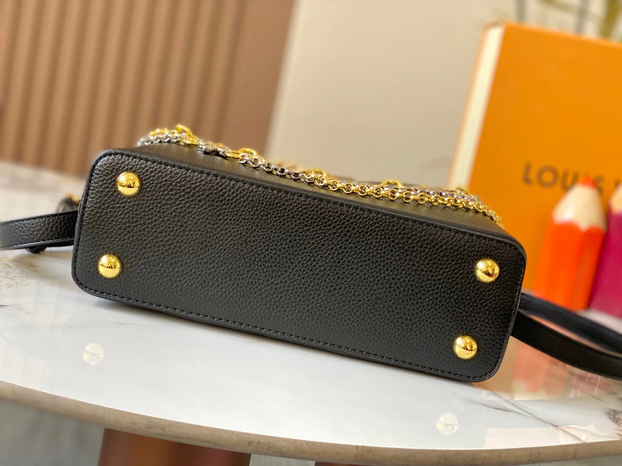 P500 [Guangzhou top quality original version] M26532 black gold. This modern version of Capucines BB is made of timeless Taurillon leather and equipped with a jewelry-inspired Infinity chain. The bag is decorated with double galvanized metal parts, including the iconic Monogram floral pattern, and the LV Initials logo created with sunburst technology, creating a sundial-like light and shadow effect. The bag has multiple pockets and a detachable shoulder strap, allowing it to be carried on one shoulder or across the body. 27 x 17.3 x 9 (cm) (length x height x width)