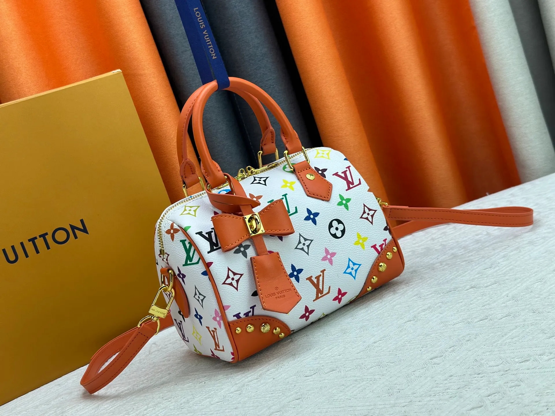 P260 upgraded original M58953 M46234 M46222 Speedy Bandoulière 20 handbag is made of soft coated canvas, and the full-length Monogram pattern is traced in colorful rainbow tones, highlighting the smart style of the Louis Vuitton x Murakami reissue series. The Toron handle and detachable shoulder strap are constructed of cow leather, the metal corners recall classic luggage elements, and the bow-shaped key bag and padlock add brand touches. Dimensions: 20.5 x 13.5 x 12.0 cm (length x height x width)