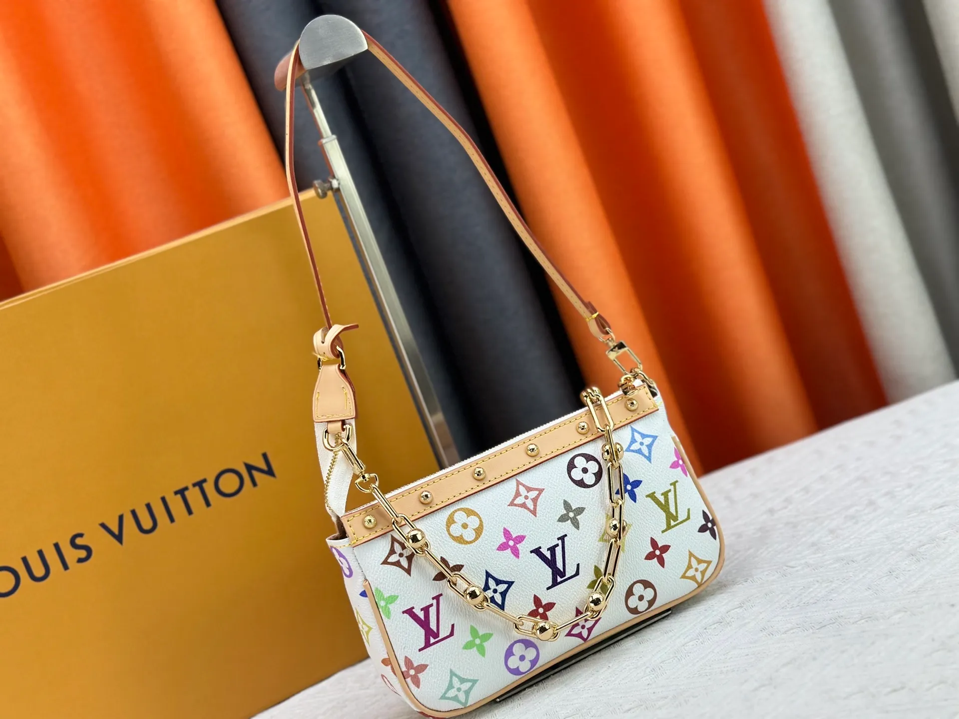 P220 M13404 M13663 Black color White color This Pochette Accessoires handbag is made of coated canvas, with colorful Monogram patterns to interpret the smart style of the Louis Vuitton × Murakami cross-border collaboration series. Calf leather trim and dazzling hardware add to the sophisticated details, while the detachable shoulder strap and chain provide flexible carry. Size: 22x13x4cm