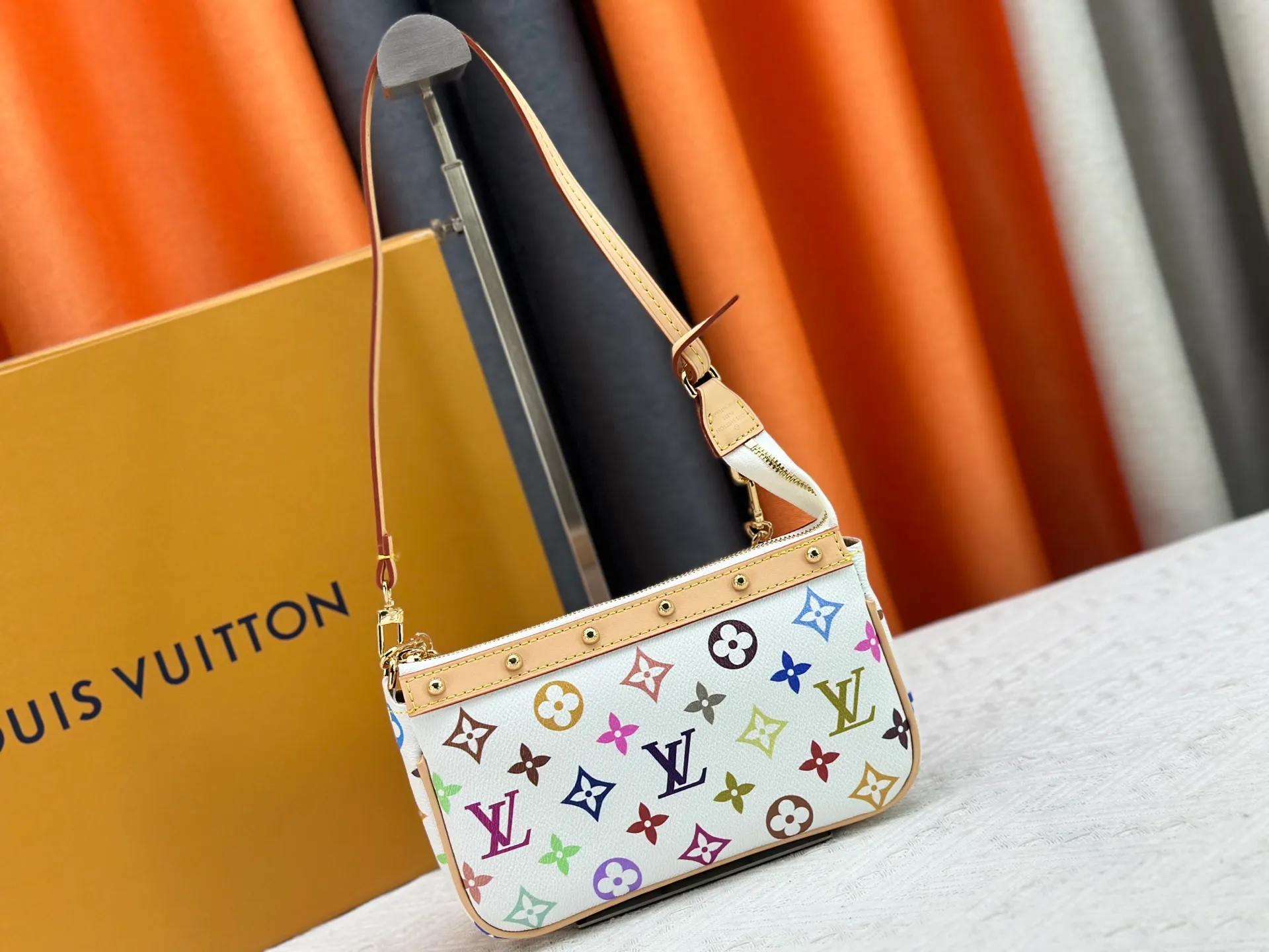 P220 M13404 M13663 Black color White color This Pochette Accessoires handbag is made of coated canvas, with colorful Monogram patterns to interpret the smart style of the Louis Vuitton × Murakami cross-border collaboration series. Calf leather trim and dazzling hardware add to the sophisticated details, while the detachable shoulder strap and chain provide flexible carry. Size: 22x13x4cm