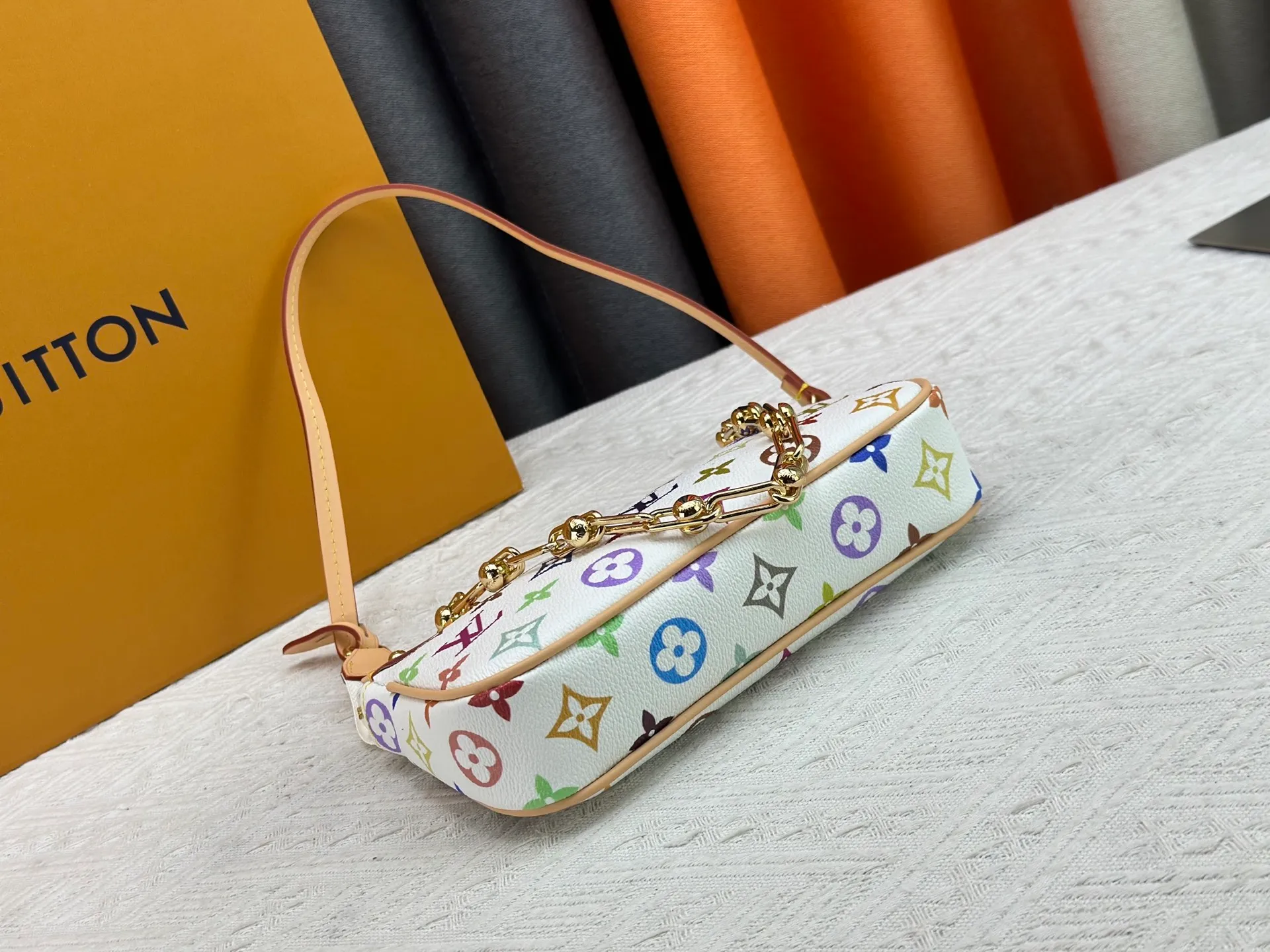 P220 M13404 M13663 Black color White color This Pochette Accessoires handbag is made of coated canvas, with colorful Monogram patterns to interpret the smart style of the Louis Vuitton × Murakami cross-border collaboration series. Calf leather trim and dazzling hardware add to the sophisticated details, while the detachable shoulder strap and chain provide flexible carry. Size: 22x13x4cm