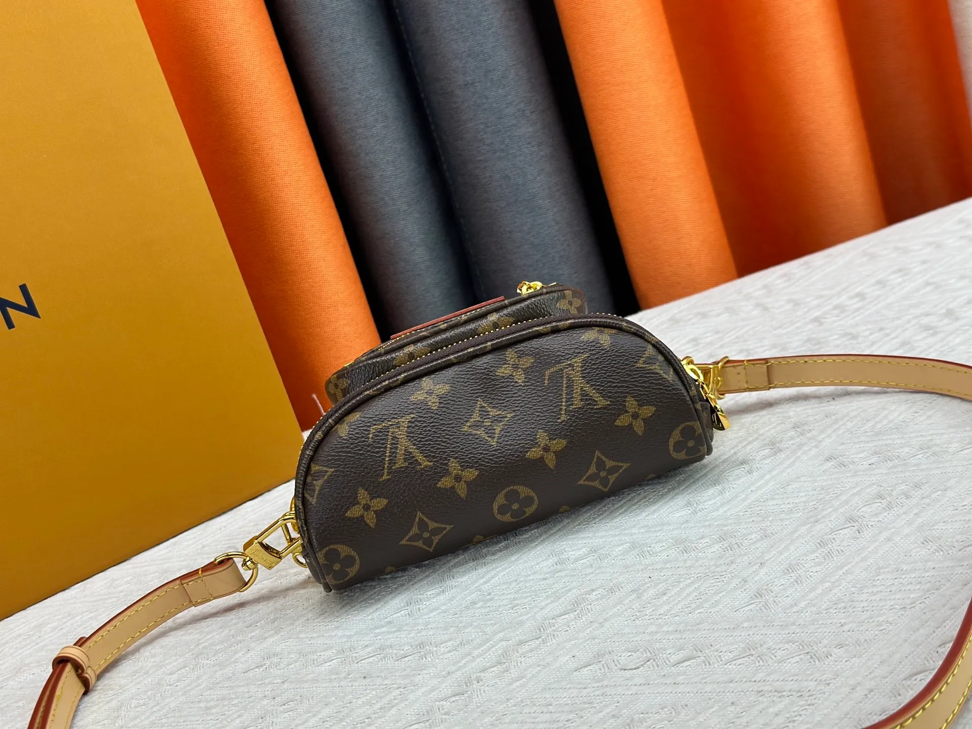 P240 M82208 M00130 M82335 This Mini Bumbag handbag comes from the LV Gradient series. The Monogram embossing of Monogram Empreinte leather renders the gradient midsummer color. The on-trend construction features a zipped main compartment and a front pocket with a Louis Vuitton leather label. With the detachable chain and detachable and adjustable shoulder strap, it can be worn as a shoulder or cross-body bag. Dimensions: 17x12x9.5 cm