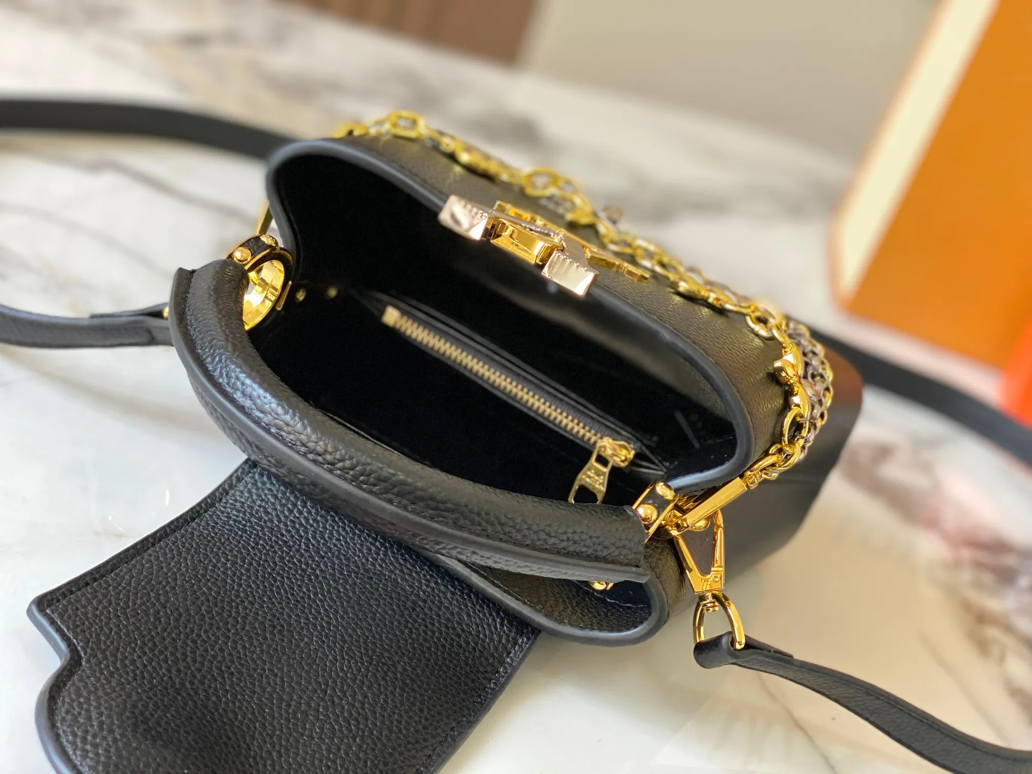 P480 [Guangzhou top quality original version] M26351 Black Gold This modern version of Capucines mini is made of timeless Taurillon leather and equipped with a jewelry-inspired Infinity chain. The bag is decorated with double galvanized metal parts, including the iconic Monogram floral pattern, and the LV Initials logo created with sunburst technology, creating a sundial-like light and shadow effect. The bag has multiple pockets and a detachable shoulder strap, allowing it to be carried on one shoulder or across the body. 14 x 8 x 21 cm (height x width x length)