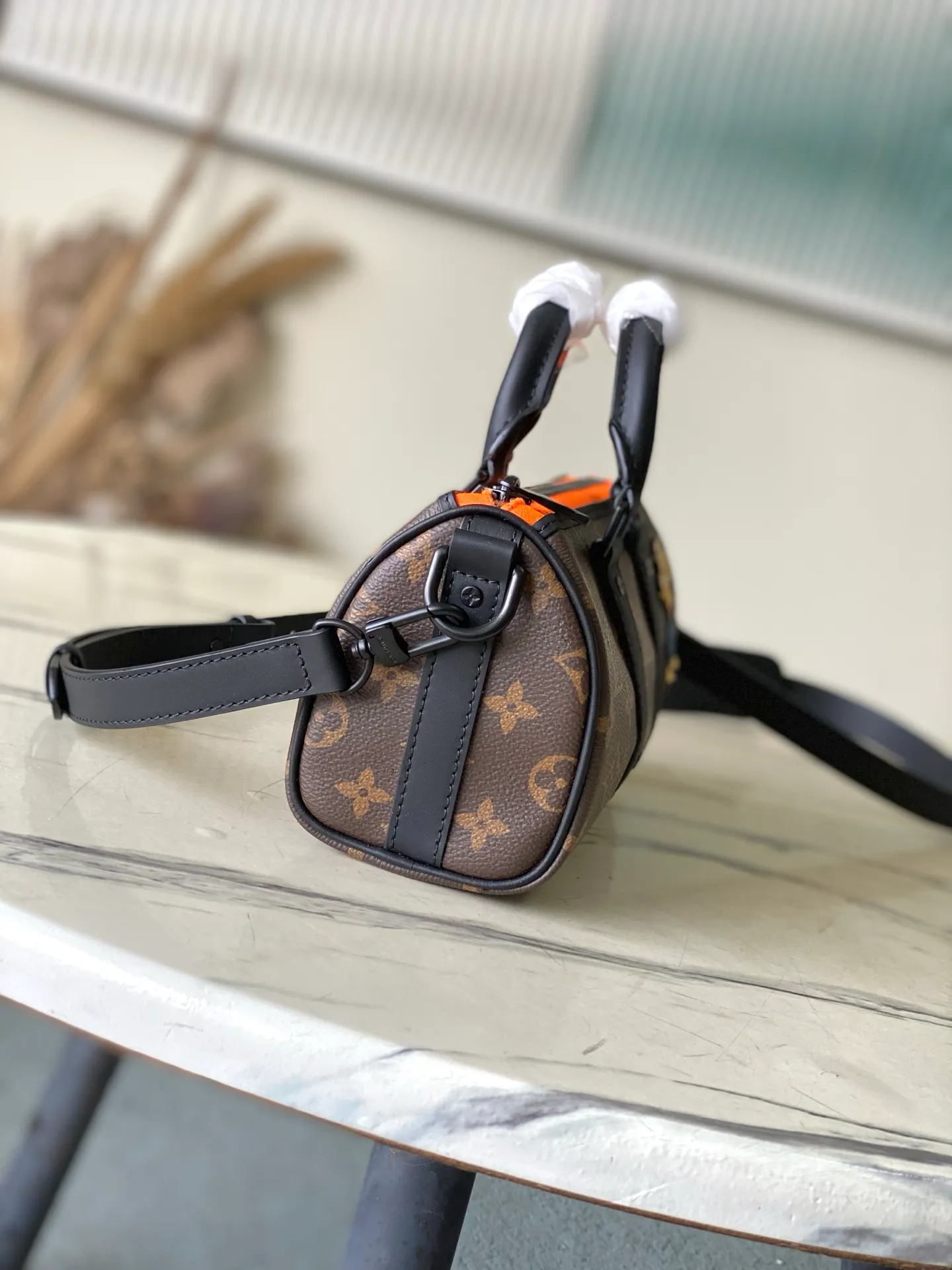 💰840 Top Original M80201 This Keepall Nano men's handbag is a compact version of the brand's original soft travel bag launched in 1930, combining Monogram canvas with black matte leather. A pop of neon orange next to the edge of the zipper makes this classic look pop. The embroidered patches feature cartoon characters from the “Zoom with friends” animated short created by menswear artistic director Virgil Abloh. Dimensions: 12 x 21 x 9 cm