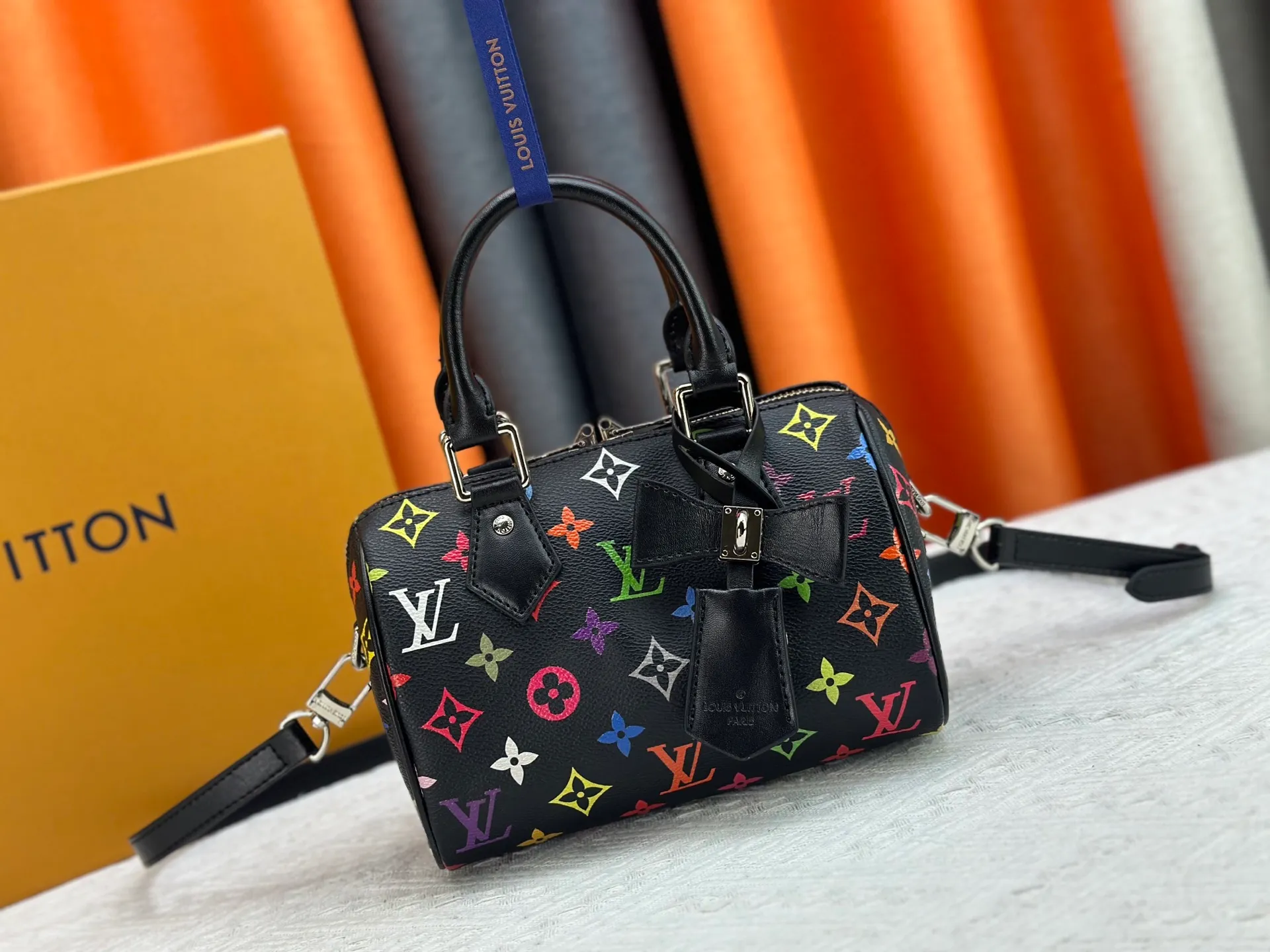 P260 Upgraded from the original version, this M46234 M46222 Speedy Bandoulière 20 handbag is made of soft coated canvas, with the full-length Monogram pattern traced in colorful rainbow tones, highlighting the smart style of the Louis Vuitton x Murakami reissue series. The Toron handle and detachable shoulder strap are constructed of cow leather, the metal corners recall classic luggage elements, and the bow-shaped key bag and padlock add brand touches. Dimensions: 20.5 x 13.5 x 12.0 cm (length x height x width)