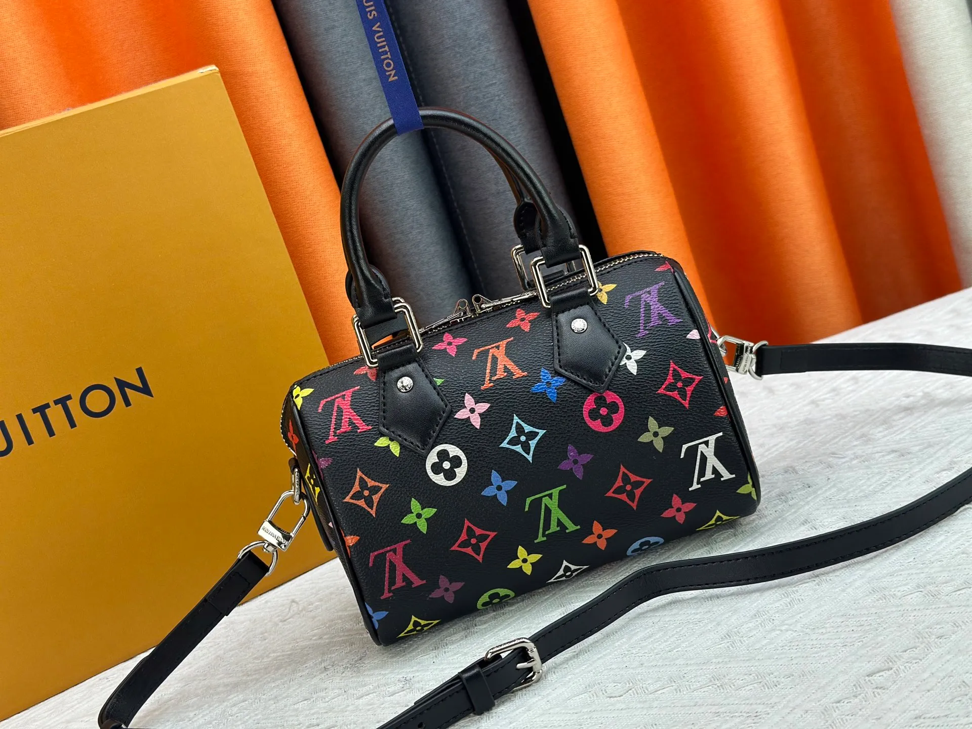 P260 Upgraded from the original version, this M46234 M46222 Speedy Bandoulière 20 handbag is made of soft coated canvas, with the full-length Monogram pattern traced in colorful rainbow tones, highlighting the smart style of the Louis Vuitton x Murakami reissue series. The Toron handle and detachable shoulder strap are constructed of cow leather, the metal corners recall classic luggage elements, and the bow-shaped key bag and padlock add brand touches. Dimensions: 20.5 x 13.5 x 12.0 cm (length x height x width)