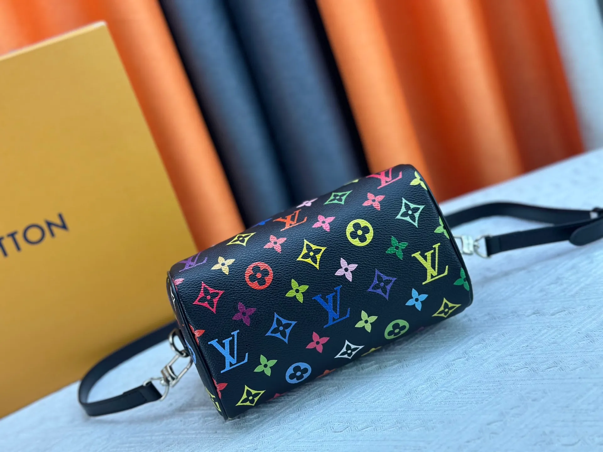 P260 Upgraded from the original version, this M46234 M46222 Speedy Bandoulière 20 handbag is made of soft coated canvas, with the full-length Monogram pattern traced in colorful rainbow tones, highlighting the smart style of the Louis Vuitton x Murakami reissue series. The Toron handle and detachable shoulder strap are constructed of cow leather, the metal corners recall classic luggage elements, and the bow-shaped key bag and padlock add brand touches. Dimensions: 20.5 x 13.5 x 12.0 cm (length x height x width)