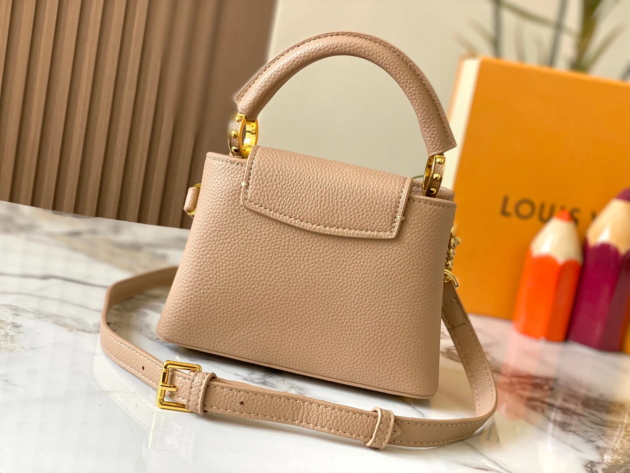 P480 [Guangzhou top quality original version] M26351 apricot color. This modern version of the Capucines mini is made of timeless Taurillon leather and equipped with a jewelry-inspired Infinity chain. The bag is decorated with double galvanized metal parts, including the iconic Monogram floral pattern, and the LV Initials logo created with sunburst technology, creating a sundial-like light and shadow effect. The bag has multiple pockets and a detachable shoulder strap, allowing it to be carried on one shoulder or across the body. 14 x 8 x 21 cm (height x width x length)