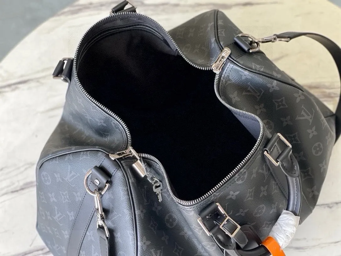 💰1040 (55 size) top original single M40605 black flower, spacious capacity, flexible use. Durable, safe and reliable. Fashionable style, mature and stable. Features a secure double zipper and padlock, making it perfect for business or pleasure. Size: 55x 31× 26cm