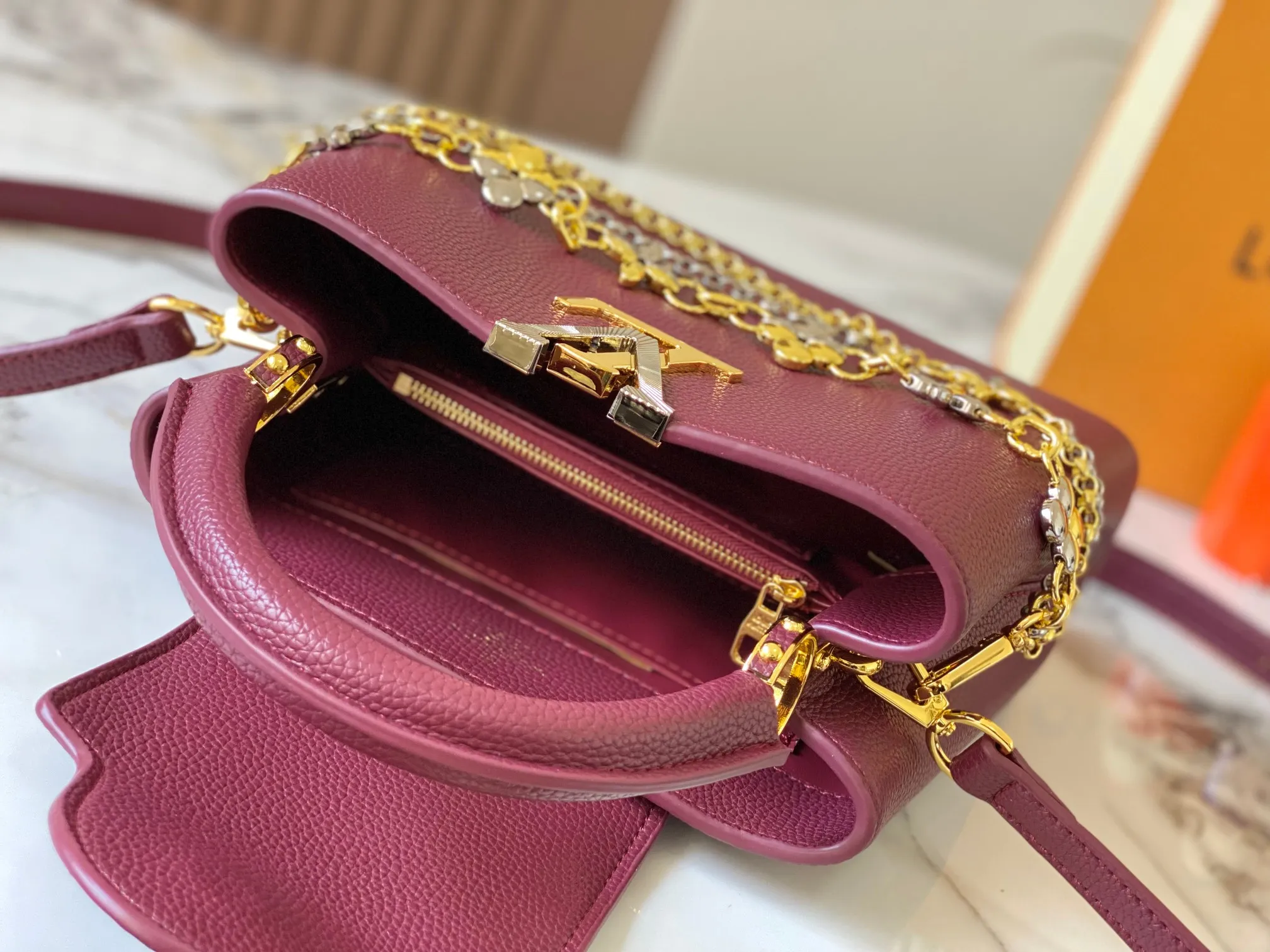 P500 [Guangzhou top quality original version] M26532 Bordeaux Red This modern version of Capucines BB is made of timeless Taurillon leather and equipped with a jewelry-inspired Infinity chain. The bag is decorated with double galvanized metal parts, including the iconic Monogram floral pattern, and the LV Initials logo created with sunburst technology, creating a sundial-like light and shadow effect. The bag has multiple pockets and a detachable shoulder strap, allowing it to be carried on one shoulder or across the body. 27 x 17.3 x 9 (cm) (length x height x width)