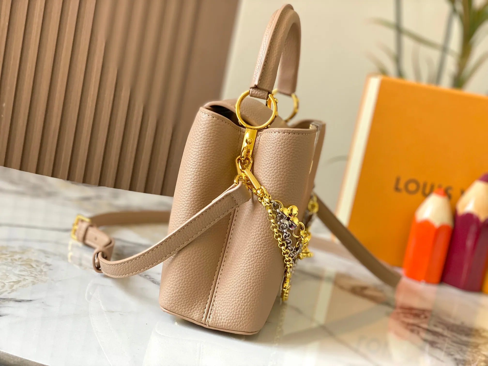 P500 [Guangzhou top quality original version] M26532 apricot color. This modern version of Capucines BB is made of timeless Taurillon leather and equipped with a jewelry-inspired Infinity chain. The bag is decorated with double galvanized metal parts, including the iconic Monogram floral pattern, and the LV Initials logo created with sunburst technology, creating a sundial-like light and shadow effect. The bag has multiple pockets and a detachable shoulder strap, allowing it to be carried on one shoulder or across the body. 27 x 17.3 x 9 (cm) (length x height x width)