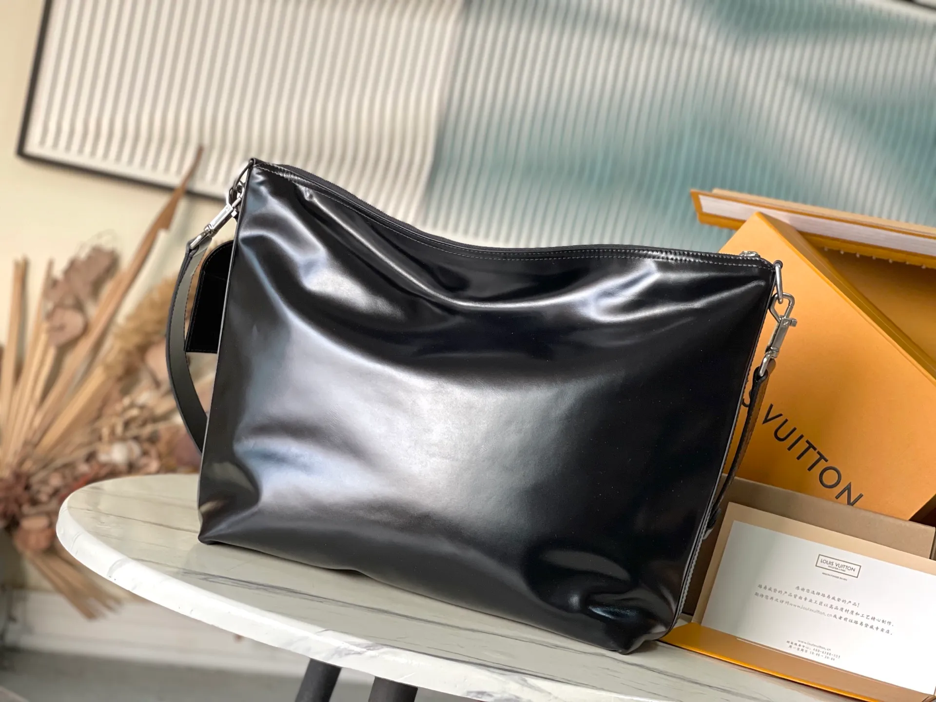 💰1280 (top-grain leather) top original order M13986 This Vagabond Hobo handbag is made of glossy soft cow leather to create an ergonomic and close-fitting silhouette. Whether it is worn cross-body or on the shoulder, it can show its cool style. The metal zipper enables smooth opening and closing, and the bead chain cleverly connects the zipper puller and V letter decoration. Dimensions: 35×12×38 cm
