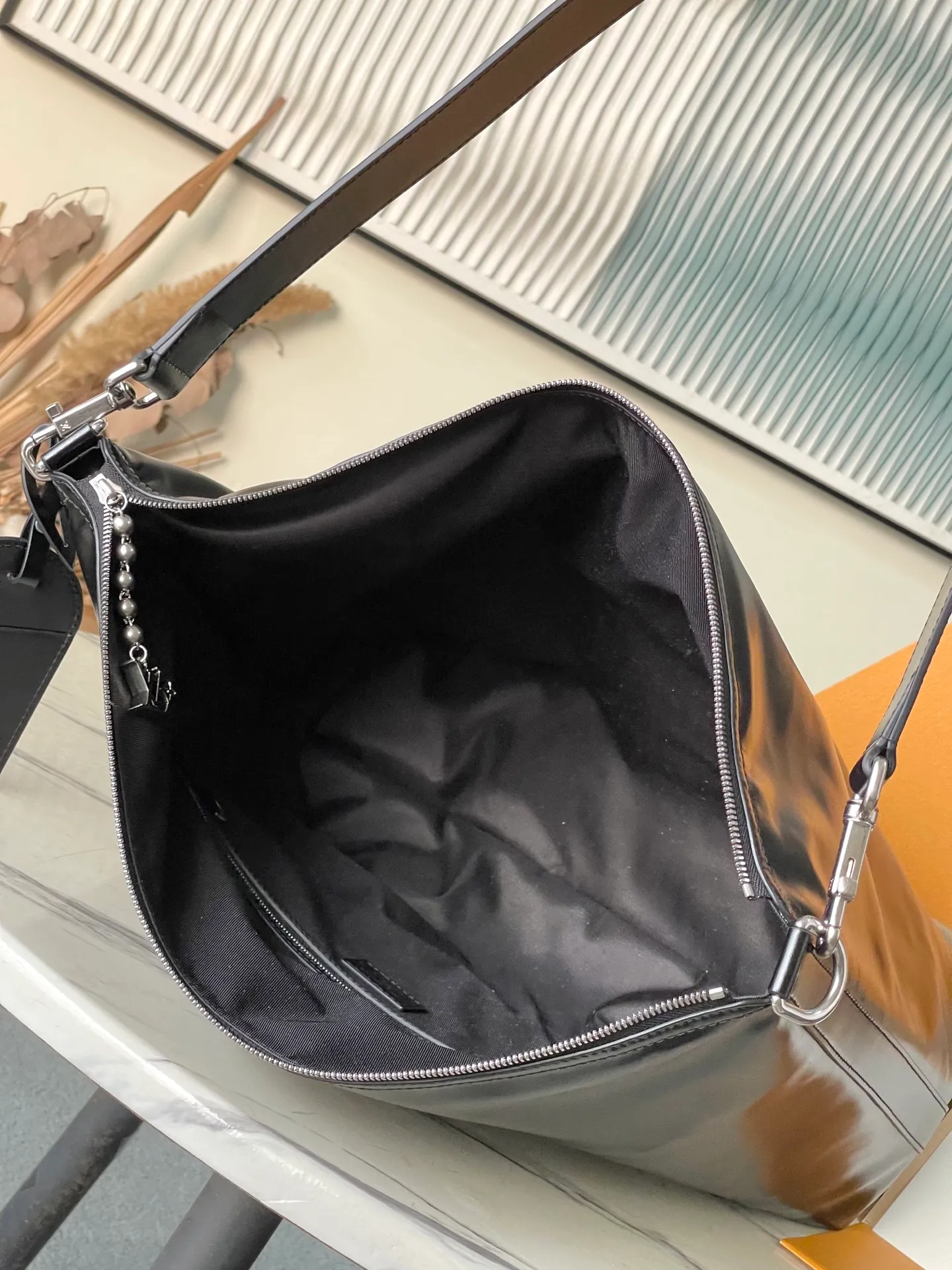 💰1280 (top-grain leather) top original order M13986 This Vagabond Hobo handbag is made of glossy soft cow leather to create an ergonomic and close-fitting silhouette. Whether it is worn cross-body or on the shoulder, it can show its cool style. The metal zipper enables smooth opening and closing, and the bead chain cleverly connects the zipper puller and V letter decoration. Dimensions: 35×12×38 cm