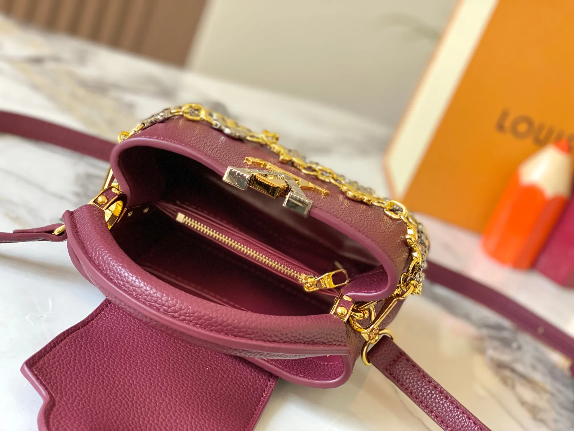 P480 [Guangzhou top quality original version] M26351 Bordeaux Red This modern version of Capucines mini is made of timeless Taurillon leather and equipped with a jewelry-inspired Infinity chain. The bag is decorated with double galvanized metal parts, including the iconic Monogram floral pattern, and the LV Initials logo created with sunburst technology, creating a sundial-like light and shadow effect. The bag has multiple pockets and a detachable shoulder strap, allowing it to be carried on one shoulder or across the body. 14 x 8 x 21 cm (height x width x length)