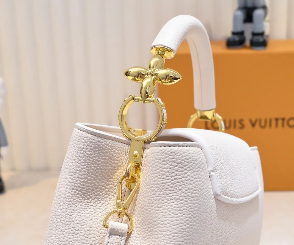 The upgraded version of the P460 M24698 Capucines BB handbag is made of Taurillon cow leather decorated with shiny metal parts, and the LV letters are written in 3D strokes. Metal Monogram flowers bloom quietly on the rolled leather handle, subtly proving the brand's exquisite craftsmanship. The detachable and adjustable leather shoulder strap allows for comfortable shoulder carrying. Detailed features 26.5 x17.5 x9 cm