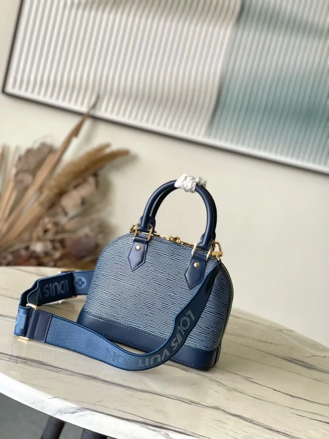 💰1500 Top original order M14853 (40302 blue and white fabric) This Alma BB bag is revisited in the latest denim blue Epi leather version. The textured effect is accompanied by a gold metallic finish, including a feature padlock and a keybell. The interior is enhanced with signature Monogram denim lining and is roomy enough to accommodate all the essentials for daily life. This model has a fabric shoulder strap to keep your hands free. 23.5 x 17.5 x 11.5 cm (LxHxW)