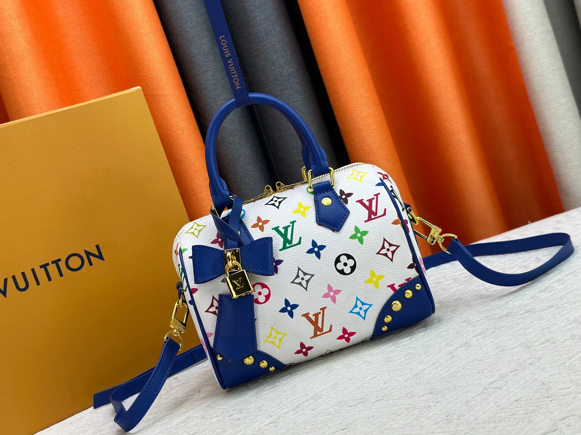 P260 upgraded original M58953 M46234 M46222 Speedy Bandoulière 20 handbag is made of soft coated canvas, and the full-length Monogram pattern is traced in colorful rainbow tones, highlighting the smart style of the Louis Vuitton x Murakami reissue series. The Toron handle and detachable shoulder strap are constructed of cow leather, the metal corners recall classic luggage elements, and the bow-shaped key bag and padlock add brand touches. Dimensions: 20.5 x 13.5 x 12.0 cm (length x height x width)
