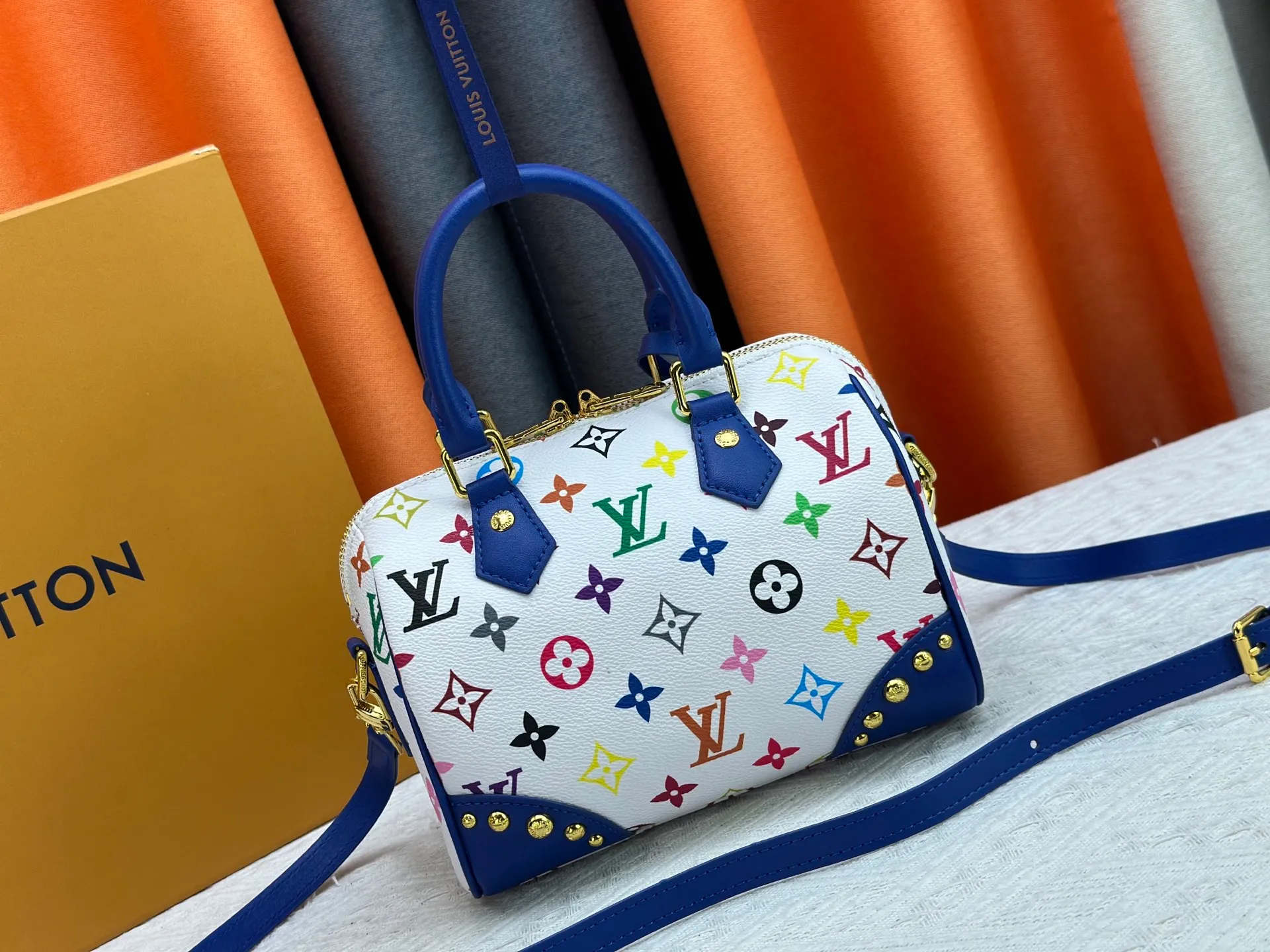 P260 upgraded original M58953 M46234 M46222 Speedy Bandoulière 20 handbag is made of soft coated canvas, and the full-length Monogram pattern is traced in colorful rainbow tones, highlighting the smart style of the Louis Vuitton x Murakami reissue series. The Toron handle and detachable shoulder strap are constructed of cow leather, the metal corners recall classic luggage elements, and the bow-shaped key bag and padlock add brand touches. Dimensions: 20.5 x 13.5 x 12.0 cm (length x height x width)