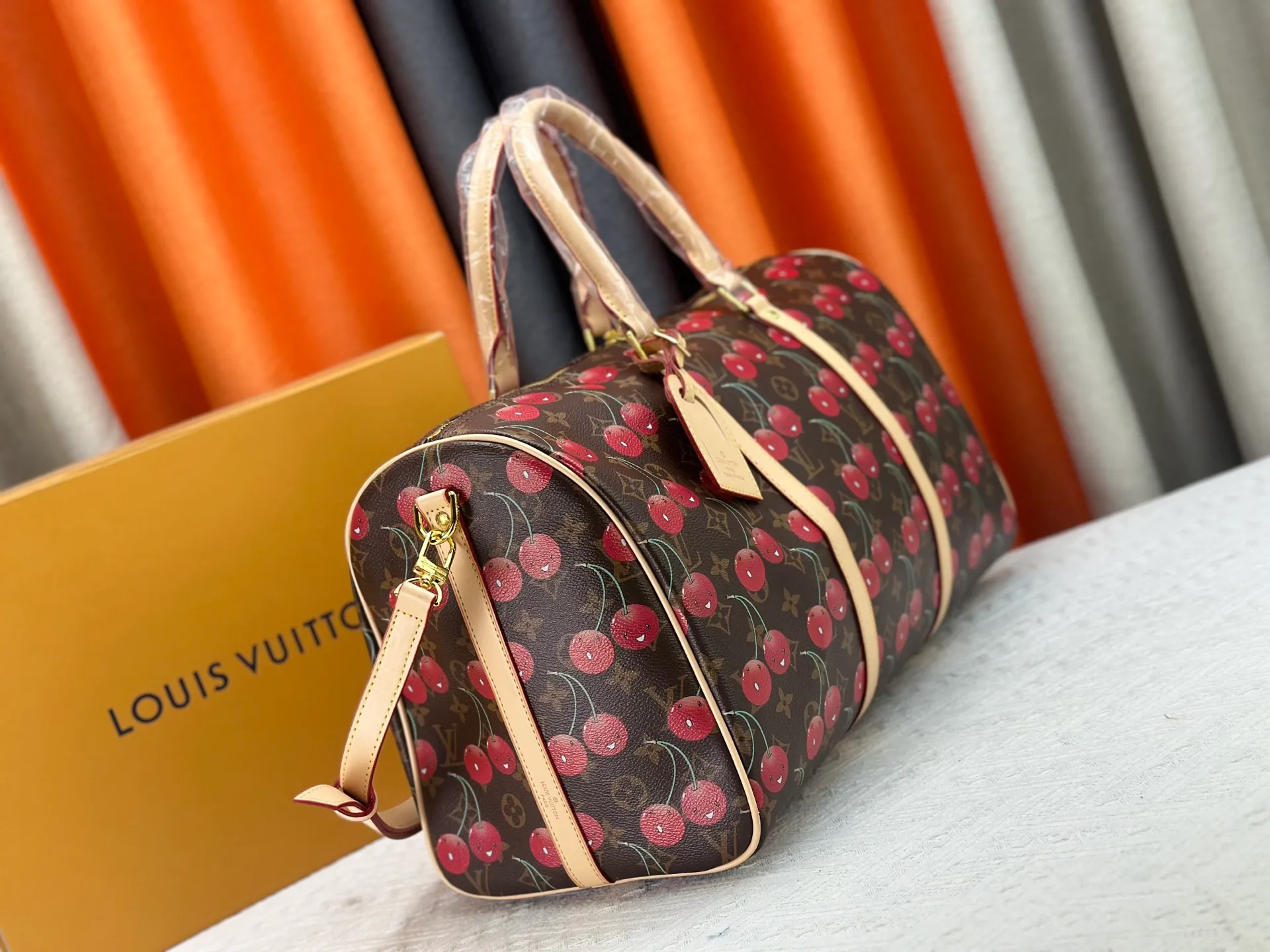 P380 M13764 M41416 Keepall Bandoulière 45 travel bag gets a new look with the Louis Vuitton x Takashi Murakami retro series. Classic Monogram canvas features a patchwork pattern of sweet cherries and a bold lining that reflects the playful aesthetic of renowned Japanese artist Takashi Murakami. Side straps, top handles and adjustable shoulder straps reveal the natural color of the leather, while dazzling hardware completes the look.  27 x 20 x 45 cm (H x W x L) Carry-on dimensions Monogram coated canvas Cow leather trim Textile lining Metal hardware Double zipper closure Internal zip pocket Padlock Designer tag, hot stampable Shoulder strap: removable, adjustable Half-length strap: 36.0 cm Half-length strap adjustable to: 50.0 cm Handle: Double handle