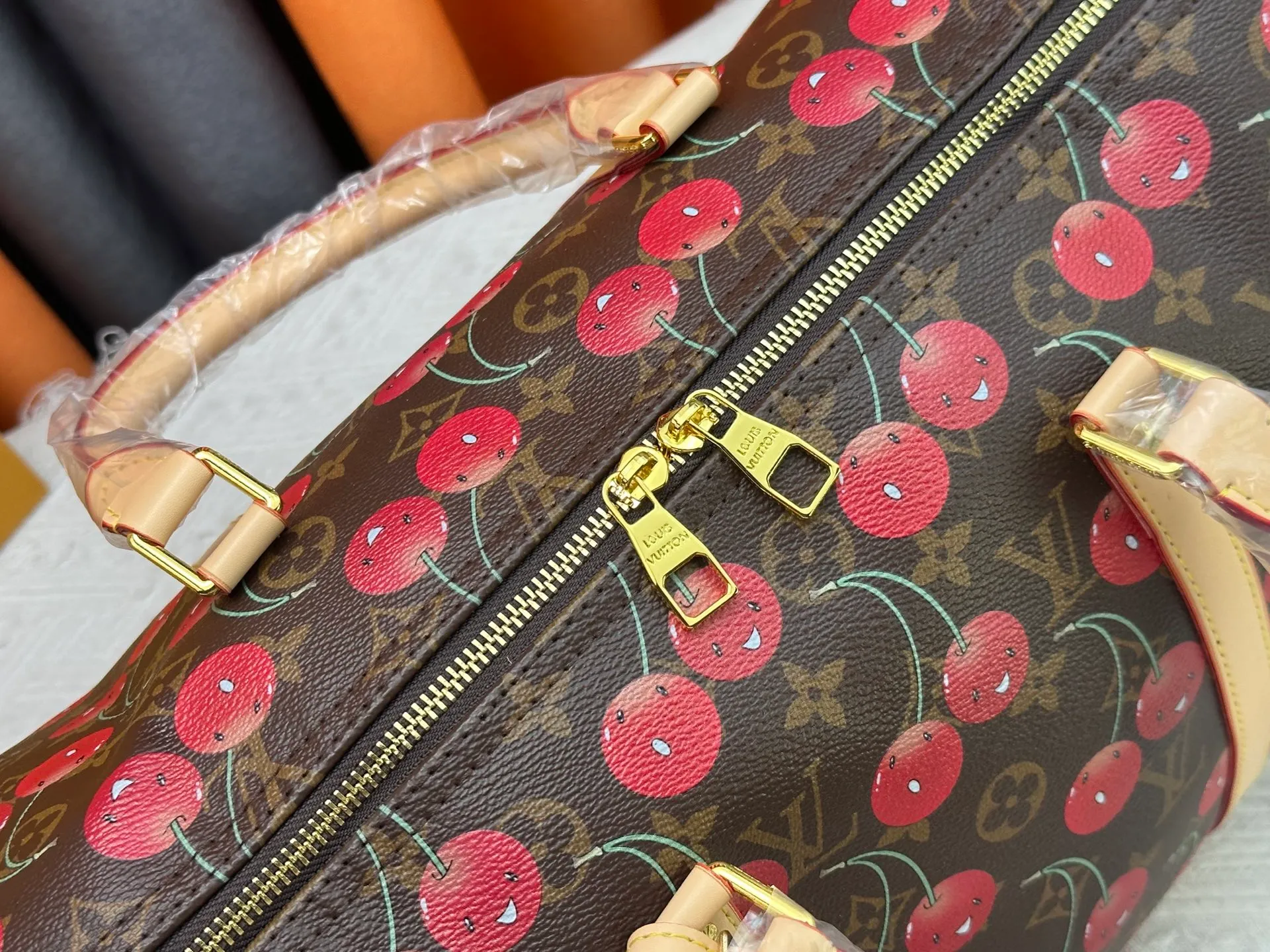 P380 M13764 M41416 Keepall Bandoulière 45 travel bag gets a new look with the Louis Vuitton x Takashi Murakami retro series. Classic Monogram canvas features a patchwork pattern of sweet cherries and a bold lining that reflects the playful aesthetic of renowned Japanese artist Takashi Murakami. Side straps, top handles and adjustable shoulder straps reveal the natural color of the leather, while dazzling hardware completes the look.  27 x 20 x 45 cm (H x W x L) Carry-on dimensions Monogram coated canvas Cow leather trim Textile lining Metal hardware Double zipper closure Internal zip pocket Padlock Designer tag, hot stampable Shoulder strap: removable, adjustable Half-length strap: 36.0 cm Half-length strap adjustable to: 50.0 cm Handle: Double handle