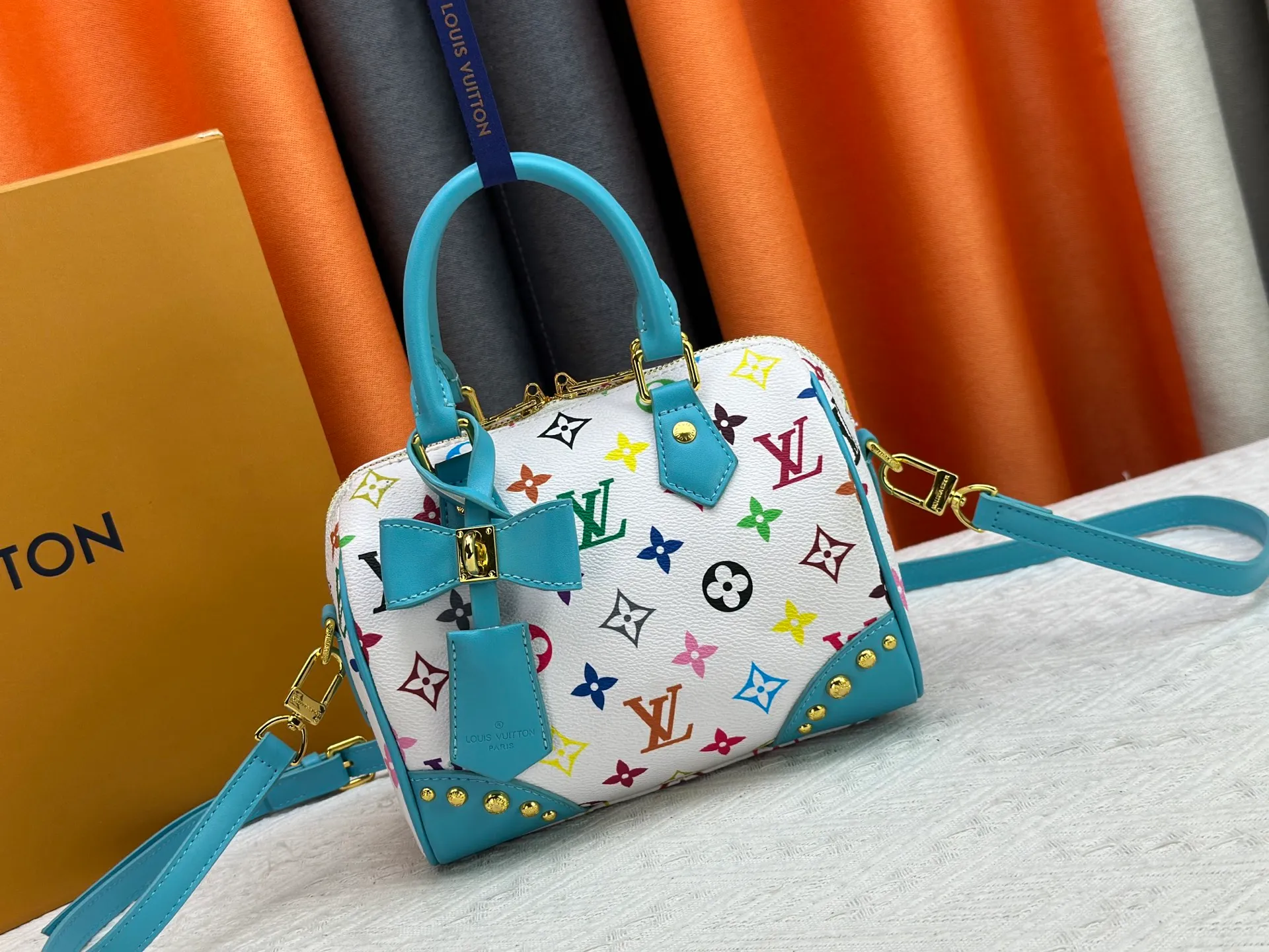 P260 upgraded original M58953 M46234 M46222 Speedy Bandoulière 20 handbag is made of soft coated canvas, and the full-length Monogram pattern is traced in colorful rainbow tones, highlighting the smart style of the Louis Vuitton x Murakami reissue series. The Toron handle and detachable shoulder strap are constructed of cow leather, the metal corners recall classic luggage elements, and the bow-shaped key bag and padlock add brand touches. Dimensions: 20.5 x 13.5 x 12.0 cm (length x height x width)