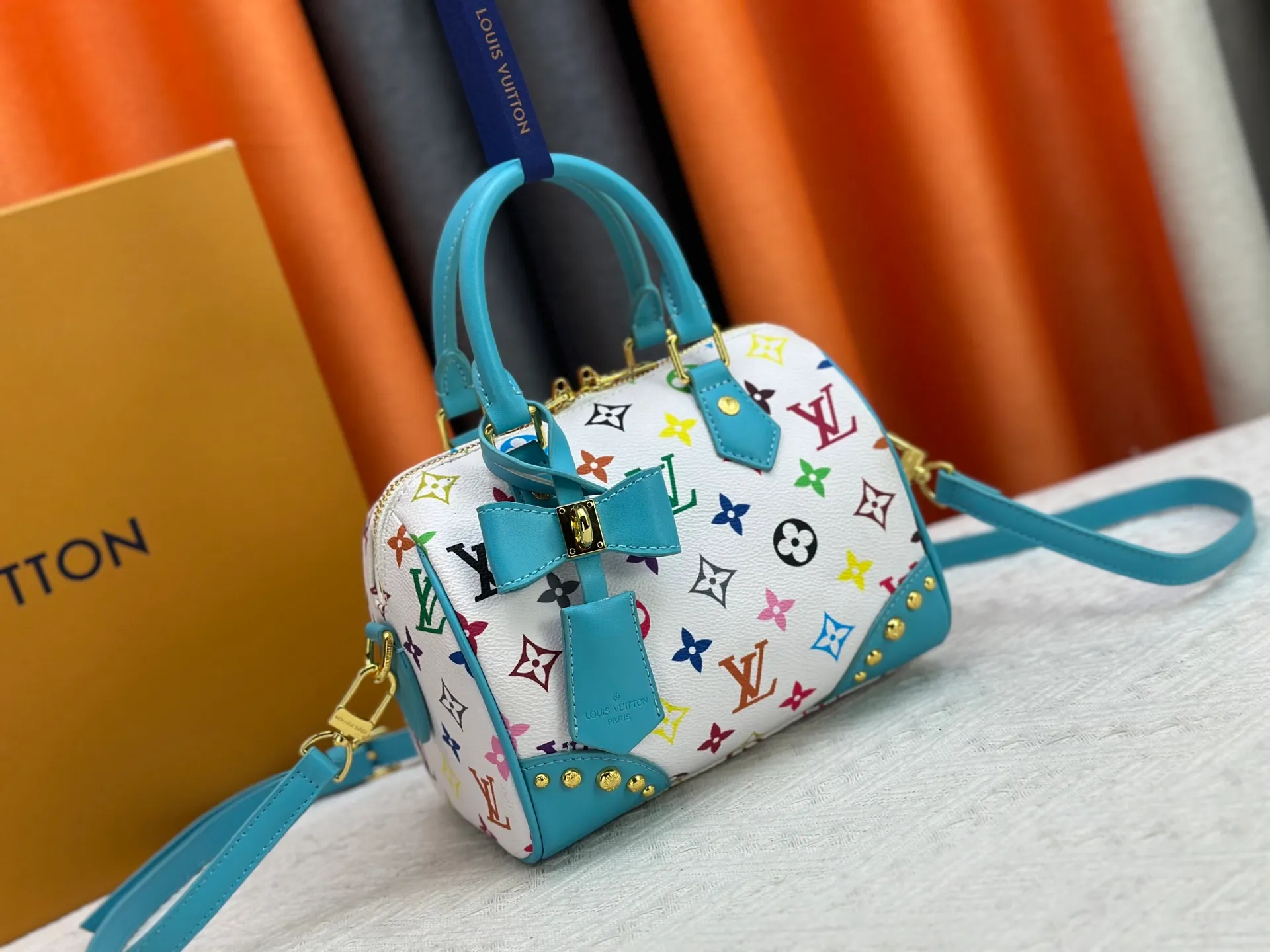 P260 upgraded original M58953 M46234 M46222 Speedy Bandoulière 20 handbag is made of soft coated canvas, and the full-length Monogram pattern is traced in colorful rainbow tones, highlighting the smart style of the Louis Vuitton x Murakami reissue series. The Toron handle and detachable shoulder strap are constructed of cow leather, the metal corners recall classic luggage elements, and the bow-shaped key bag and padlock add brand touches. Dimensions: 20.5 x 13.5 x 12.0 cm (length x height x width)