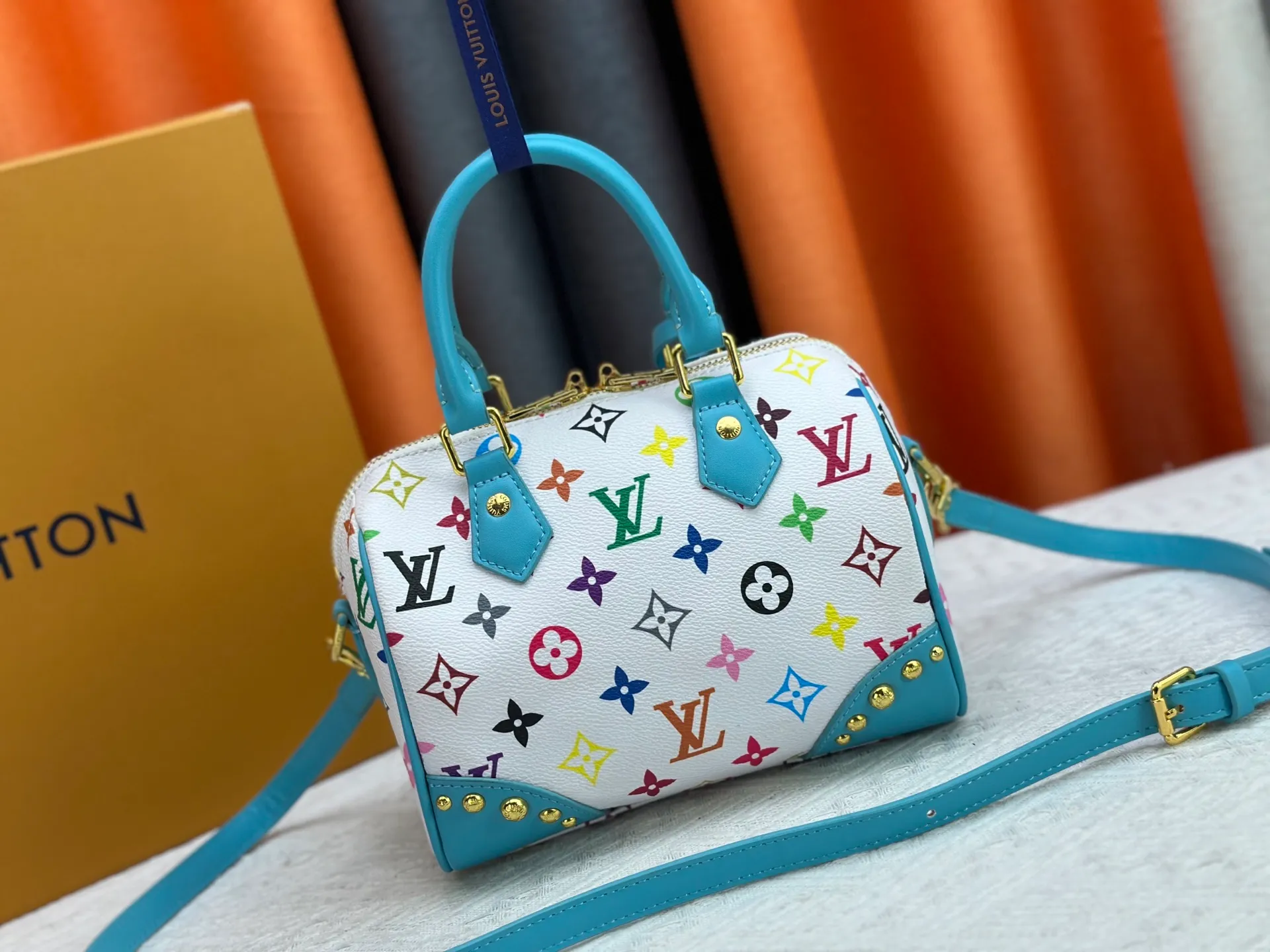 P260 upgraded original M58953 M46234 M46222 Speedy Bandoulière 20 handbag is made of soft coated canvas, and the full-length Monogram pattern is traced in colorful rainbow tones, highlighting the smart style of the Louis Vuitton x Murakami reissue series. The Toron handle and detachable shoulder strap are constructed of cow leather, the metal corners recall classic luggage elements, and the bow-shaped key bag and padlock add brand touches. Dimensions: 20.5 x 13.5 x 12.0 cm (length x height x width)