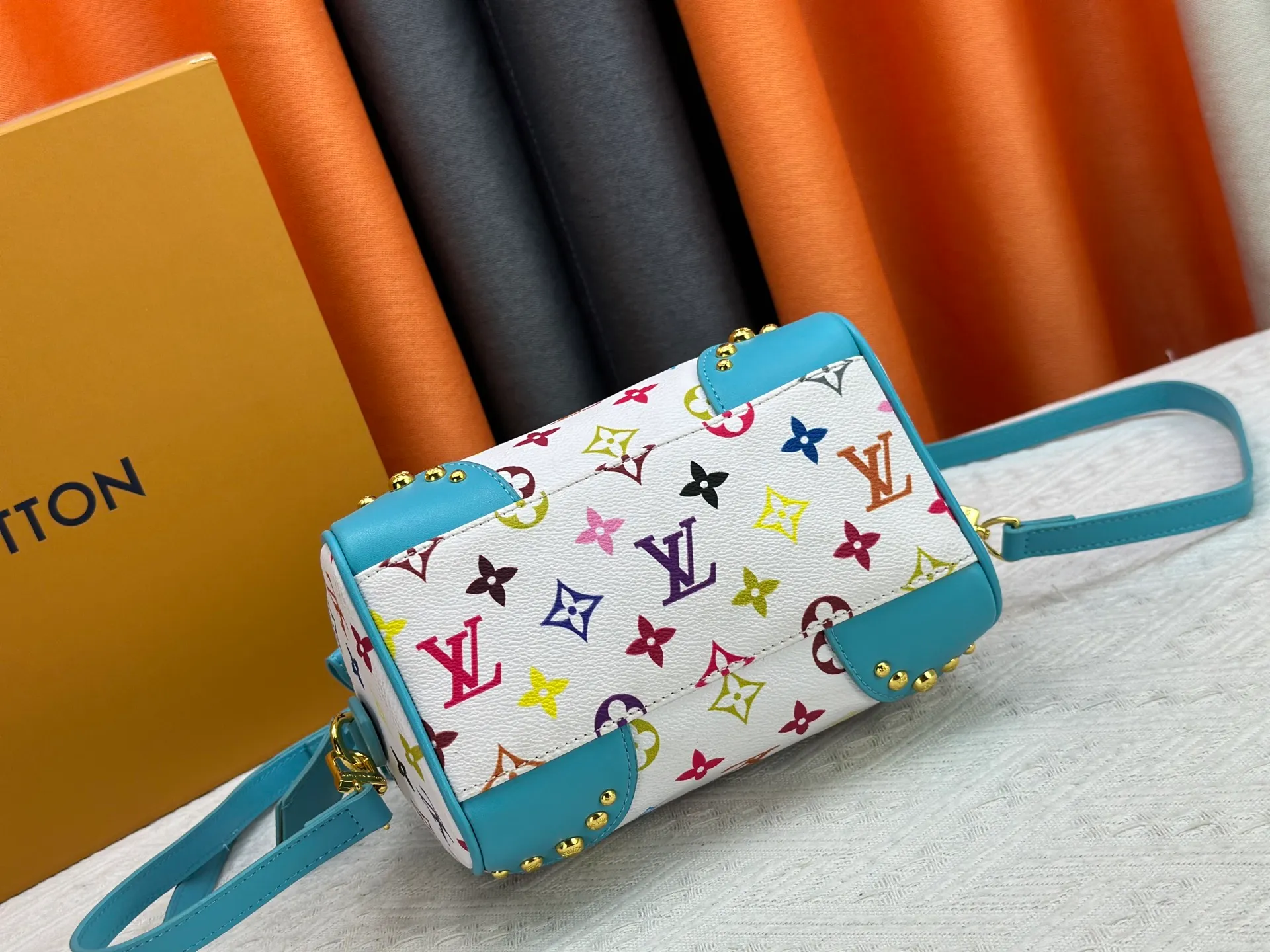 P260 upgraded original M58953 M46234 M46222 Speedy Bandoulière 20 handbag is made of soft coated canvas, and the full-length Monogram pattern is traced in colorful rainbow tones, highlighting the smart style of the Louis Vuitton x Murakami reissue series. The Toron handle and detachable shoulder strap are constructed of cow leather, the metal corners recall classic luggage elements, and the bow-shaped key bag and padlock add brand touches. Dimensions: 20.5 x 13.5 x 12.0 cm (length x height x width)