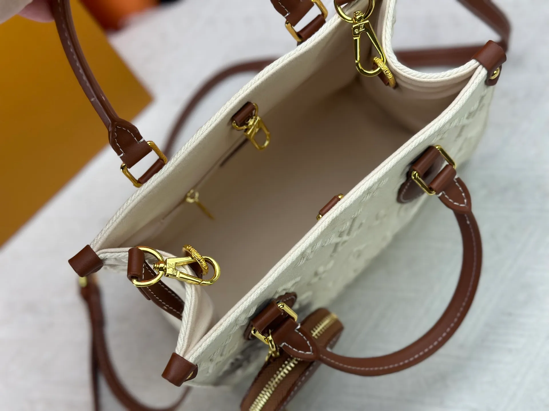 P300 M45659 M46373 Apricot embossed denim OnTheGo small new version The legendary ONTHEGO handbag: made of washed LV Blason denim, with deep tones to accentuate the gradient effect of the LV letters, showing Pharrell Williams' creative ingenuity in translating graceful music into fashion language. The zippered front pocket provides easy access to everyday items, while the drawstring closure and magnetic laces provide ample space. Detailed features25x11x19 cm