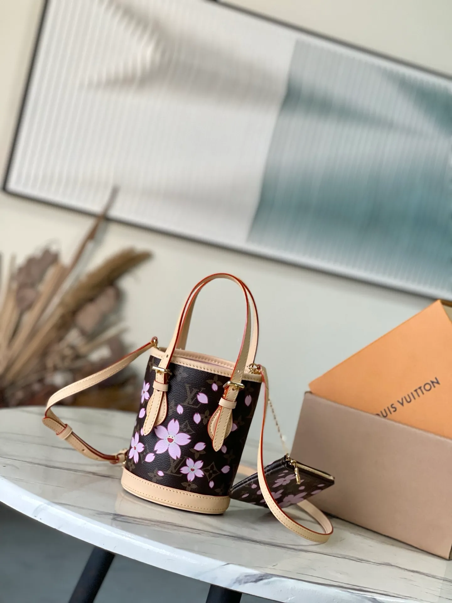 💰900 Top Original Order M13417 This Nano Bucket handbag is constructed of classic Monogram coated canvas with a sophisticated design, and is completed with cow leather trim and dazzling metal parts. The Cherry Blossom pattern on the body of the bag conveys the atmosphere of prosperous recovery and highlights the distinctive style of Japanese artist Takashi Murakami. The detachable shoulder strap allows for a variety of carrying options, and the leather keychain adds a functional detail. Dimensions: 13 × 17 × 9 cm