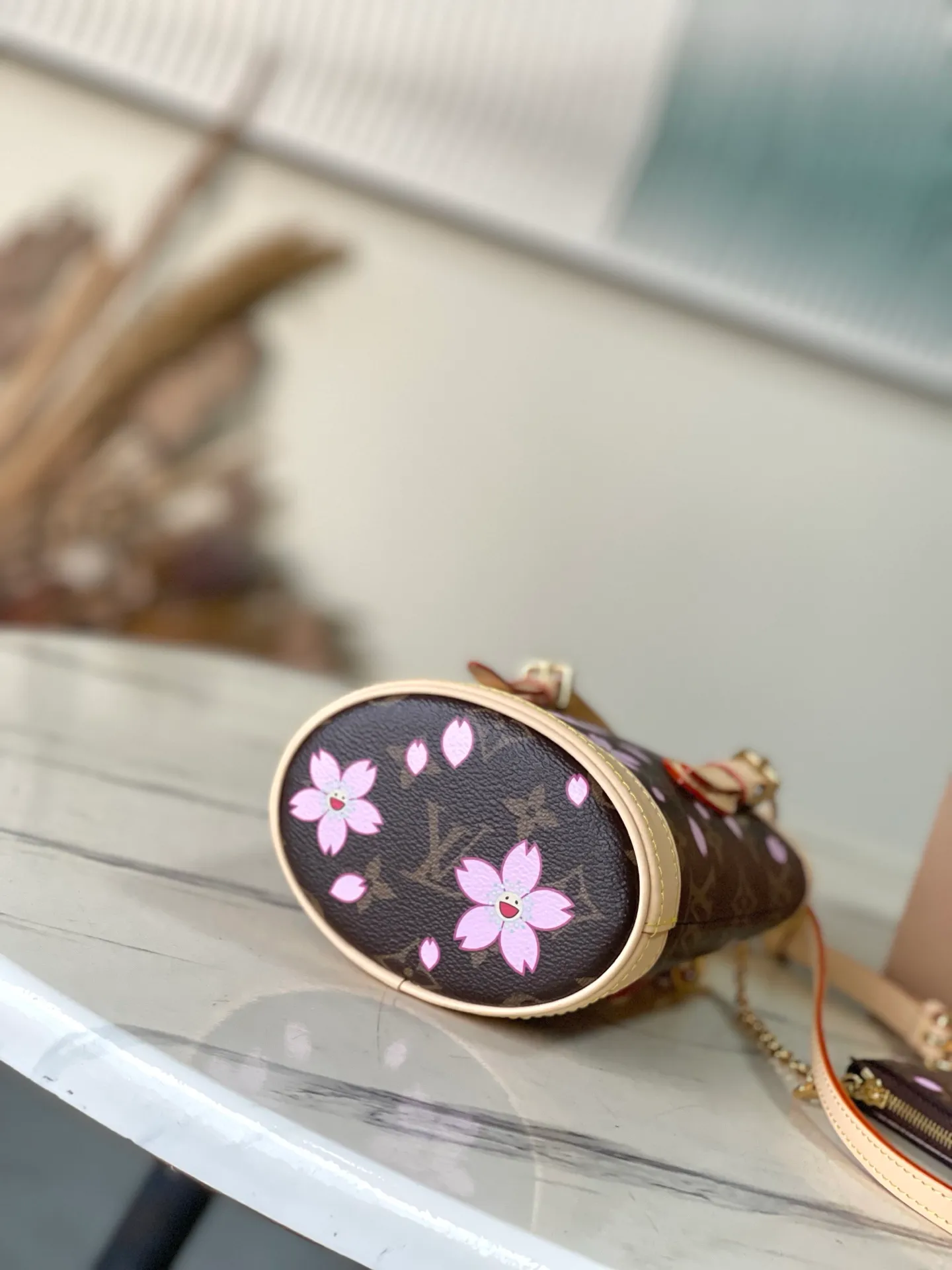 💰900 Top Original Order M13417 This Nano Bucket handbag is constructed of classic Monogram coated canvas with a sophisticated design, and is completed with cow leather trim and dazzling metal parts. The Cherry Blossom pattern on the body of the bag conveys the atmosphere of prosperous recovery and highlights the distinctive style of Japanese artist Takashi Murakami. The detachable shoulder strap allows for a variety of carrying options, and the leather keychain adds a functional detail. Dimensions: 13 × 17 × 9 cm