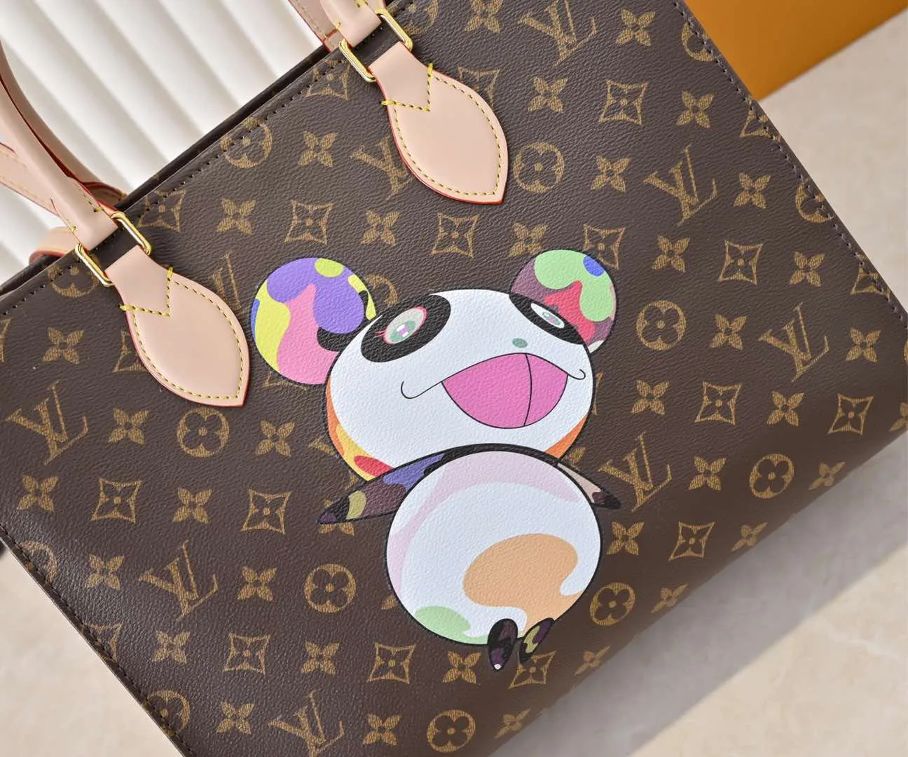 Batch 320💰M45039 M13668!🔥Lv&Takashi Murakami🐼Panda print OnTheGo new version The legendary ONTHEGO handbag: always able to meet your various needs for handbags. It has a large capacity but is not bulky. It is stiff and soft to the touch, making it suitable for home and travel. Tighten the side ties and it instantly transforms into a stylish urban handbag. Loosen the straps and it transforms into a chic and practical handbag. The slender leather handle can be carried over the shoulder or between the arms. The model shown here is made of Damier Azur canvas. Size: 35x27x14cm