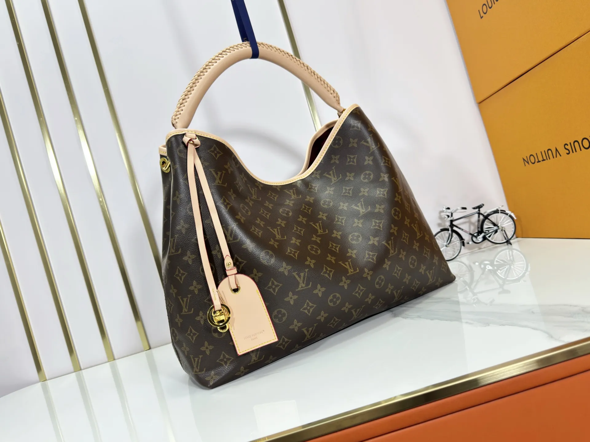 P280 upgrades the original M25877 Again handbag, a new interpretation of the iconic Artsy design first launched in 2010, now more flexible, more iconic and more refined. Rooted in LV’s DNA, this bag pays homage to Louis Vuitton’s craftsmanship with its classic Monogram canvas base, hand-woven handles and customizable name tag. It's spacious enough to hold a laptop and opens to reveal multiple pockets. Gold hooks can be used to hang playful accessories! ! Size:50x30x15.5CM