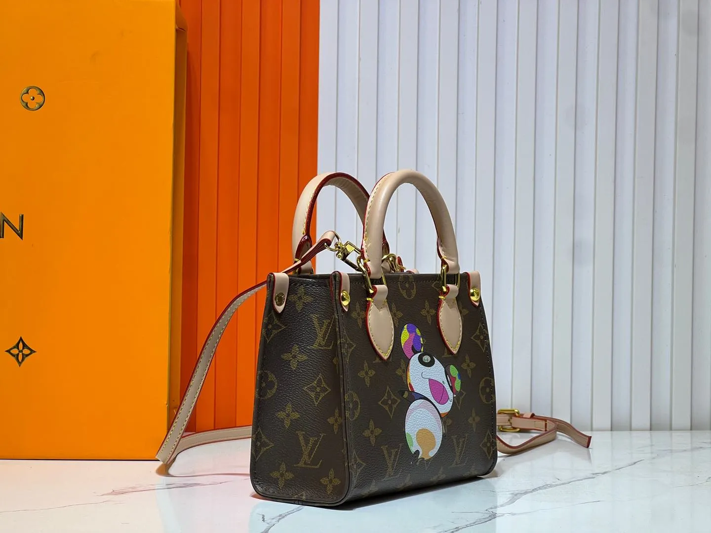 Batch 260💰M46993 M13668!🔥Lv&Takashi Murakami🐼Panda print OnTheGo BB new version The legendary ONTHEGO handbag: always able to meet your various needs for handbags. It has a large capacity but is not bulky. It is stiff and soft to the touch, making it suitable for home and travel. Tighten the side ties and it instantly transforms into a stylish urban handbag. Loosen the straps and it transforms into a chic and practical handbag. The slender leather handle can be carried over the shoulder or between the arms. The model shown here is made of Damier Azur canvas. Size: 18x15x8.5cm