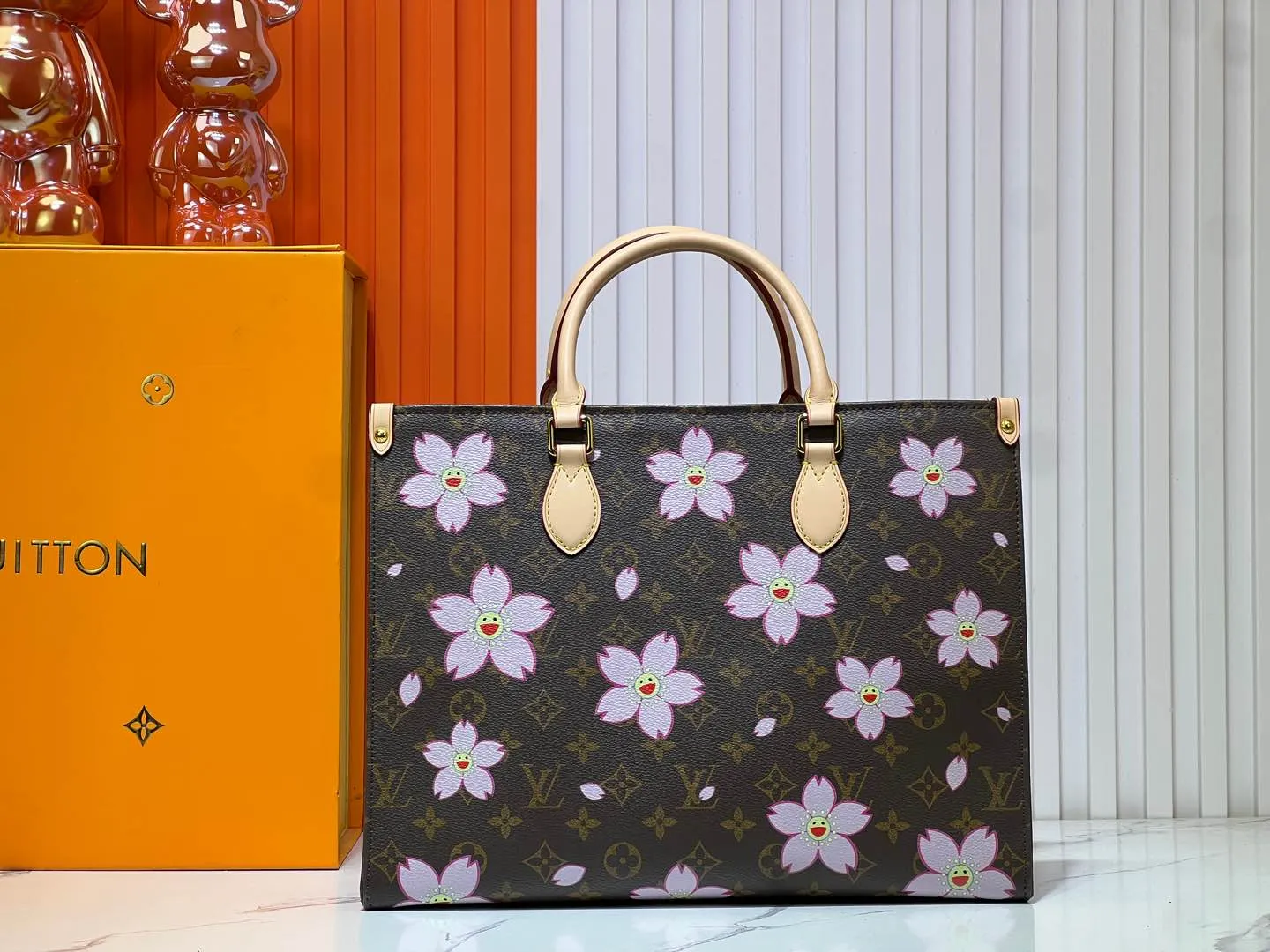 Batch 280💰M45039 M13668!🔥Lv&Takashi Murakami Sakura🌸OnTheGo new version The legendary ONTHEGO handbag: always able to meet your various needs for handbags. It has a large capacity but is not bulky. It is stiff and soft to the touch, making it suitable for home and travel. Tighten the side ties and it instantly transforms into a stylish urban handbag. Loosen the straps and it transforms into a chic and practical handbag. The slender leather handle can be carried over the shoulder or between the arms. The model shown here is made of Damier Azur canvas. Size: 35x27x14cm