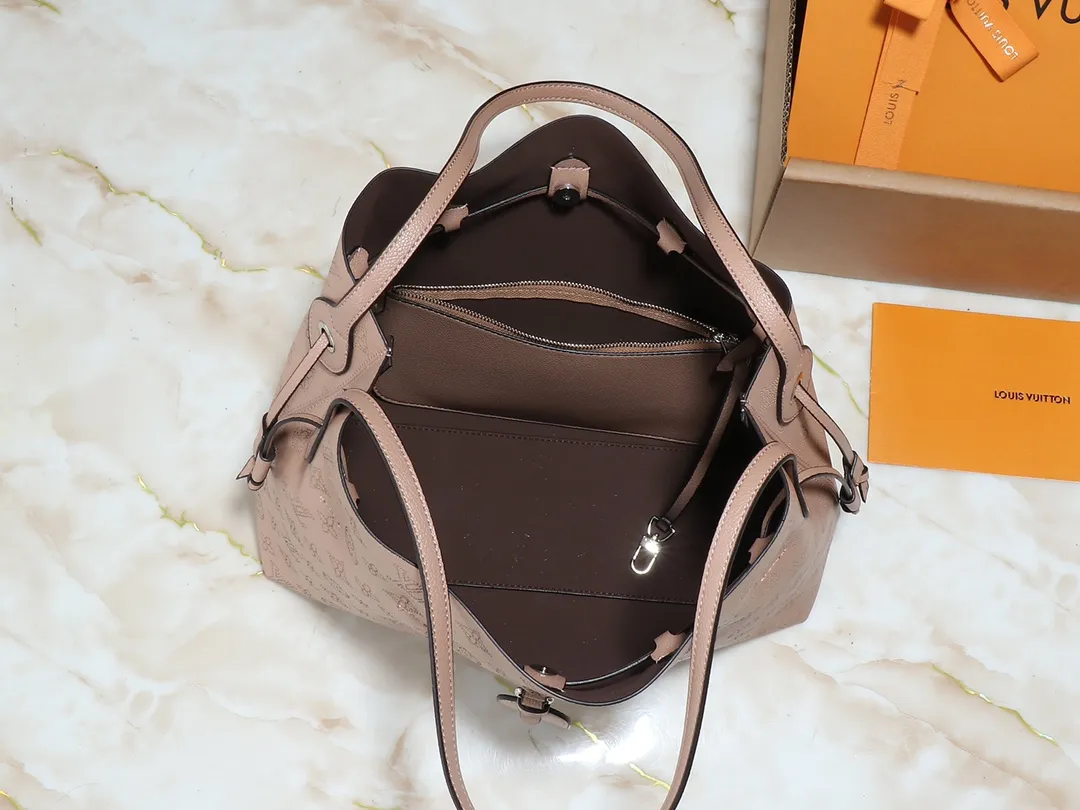 💰280💰Upgraded from the original M13180 Mahina series introduces the Boundless handbag - a multi-functional daily design. It's made from House's signature perforated Mahina leather and is roomy enough to store essential items, including a laptop and tablet. The shoulder bag features a removable zip pocket and is embellished with silver hardware for a sophisticated look. Dimensions: 16.9 x 13.2 x 6.7 inches (LxHxW)