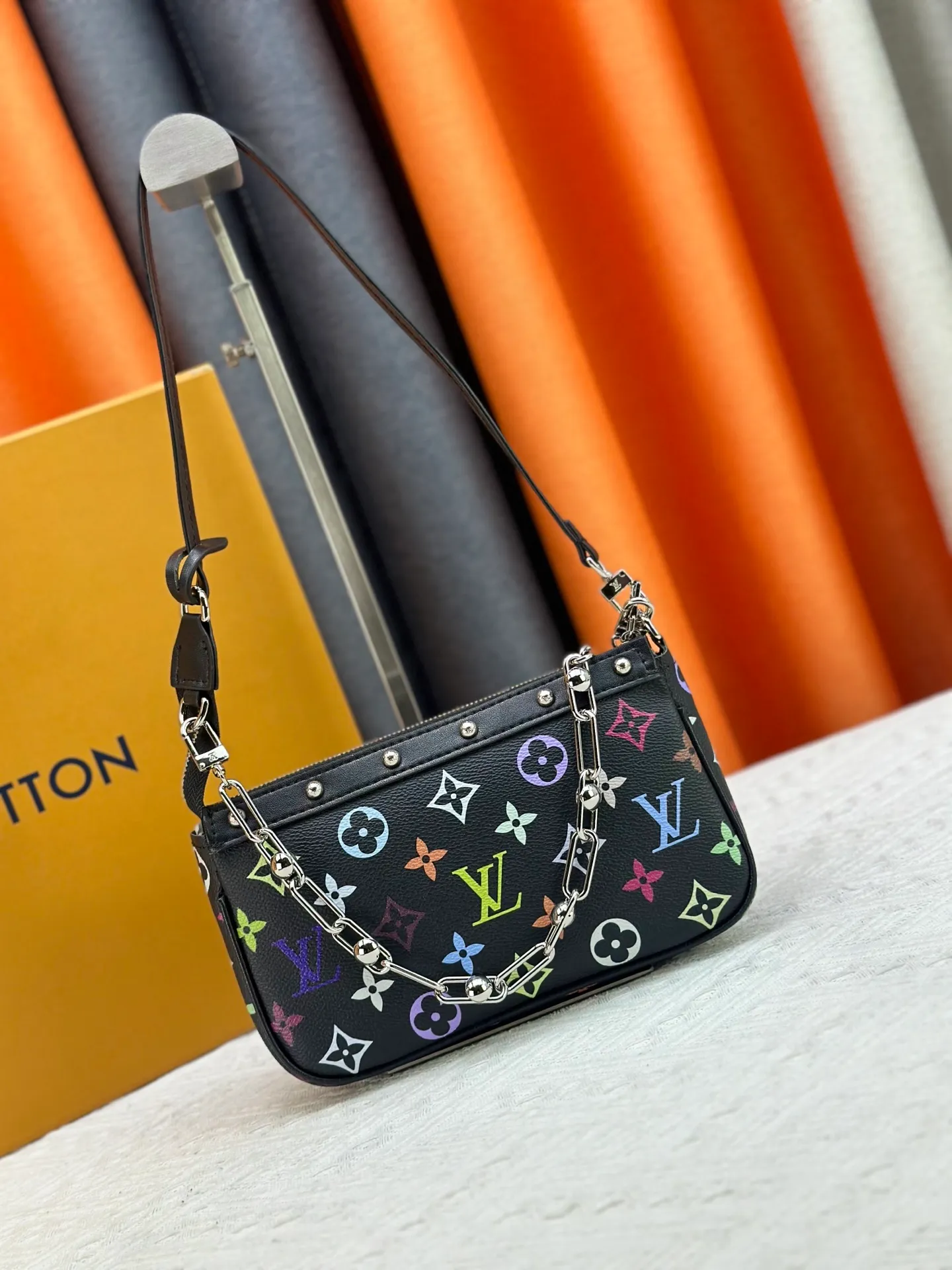 P220 M13404 M13663 Black color White color This Pochette Accessoires handbag is made of coated canvas, with colorful Monogram patterns to interpret the smart style of the Louis Vuitton × Murakami cross-border collaboration series. Calf leather trim and dazzling hardware add to the sophisticated details, while the detachable shoulder strap and chain provide flexible carry. Size: 22x13x4cm