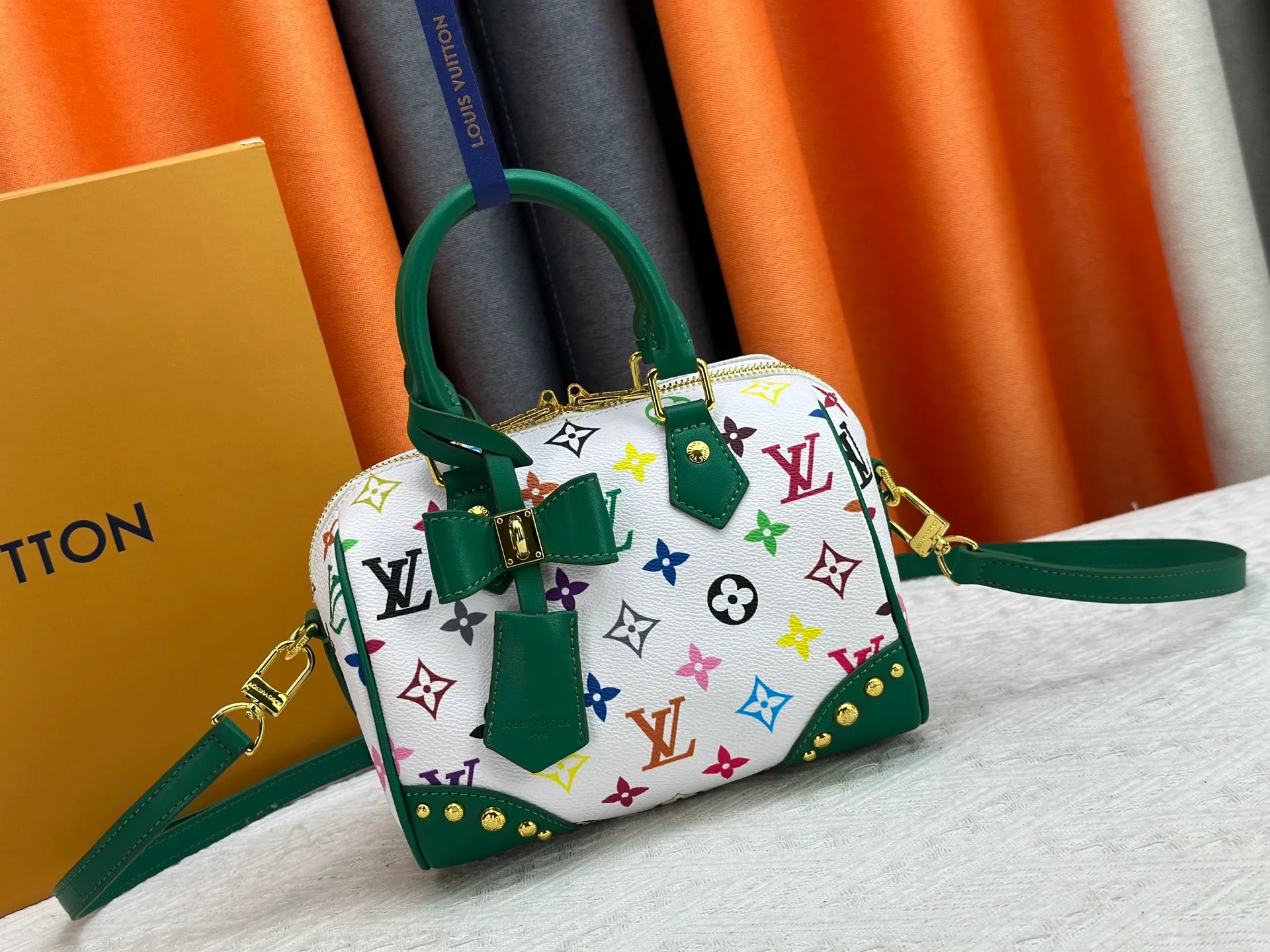 P260 upgraded original M58953 M46234 M46222 Speedy Bandoulière 20 handbag is made of soft coated canvas, and the full-length Monogram pattern is traced in colorful rainbow tones, highlighting the smart style of the Louis Vuitton x Murakami reissue series. The Toron handle and detachable shoulder strap are constructed of cow leather, the metal corners recall classic luggage elements, and the bow-shaped key bag and padlock add brand touches. Dimensions: 20.5 x 13.5 x 12.0 cm (length x height x width)