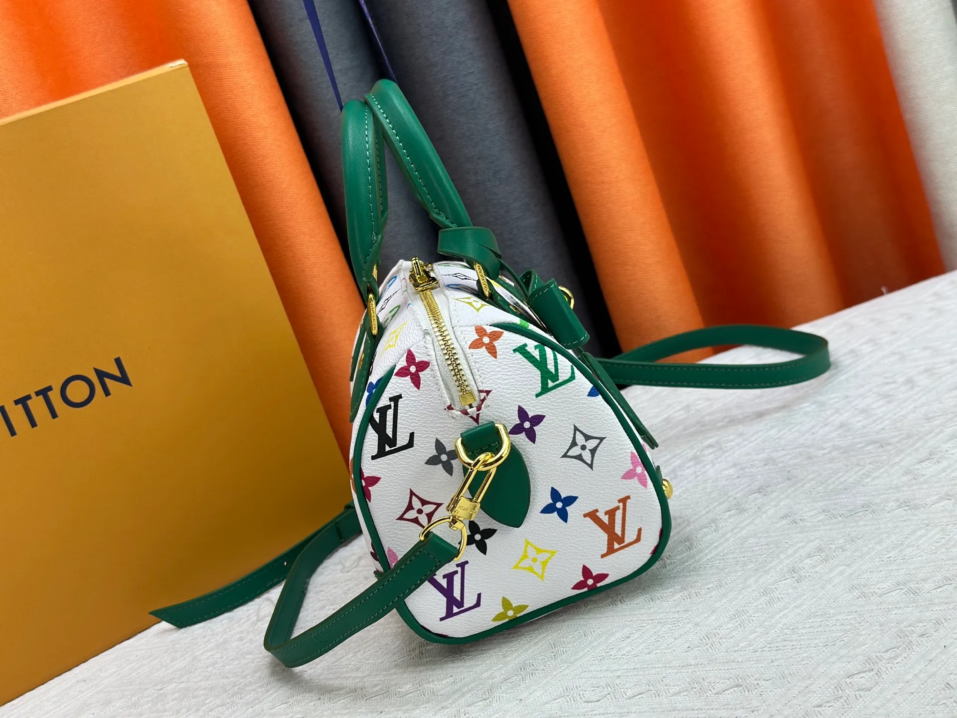 P260 upgraded original M58953 M46234 M46222 Speedy Bandoulière 20 handbag is made of soft coated canvas, and the full-length Monogram pattern is traced in colorful rainbow tones, highlighting the smart style of the Louis Vuitton x Murakami reissue series. The Toron handle and detachable shoulder strap are constructed of cow leather, the metal corners recall classic luggage elements, and the bow-shaped key bag and padlock add brand touches. Dimensions: 20.5 x 13.5 x 12.0 cm (length x height x width)