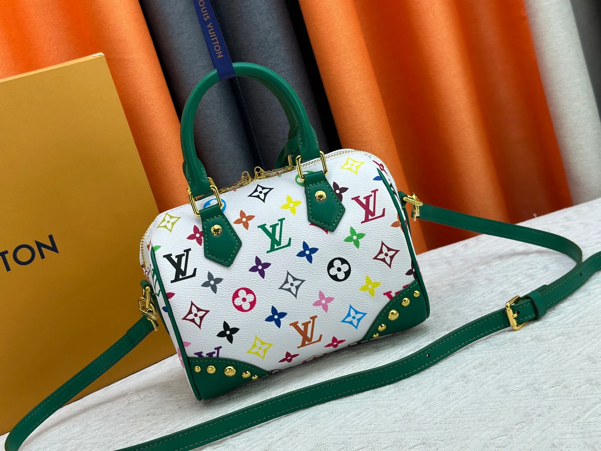 P260 upgraded original M58953 M46234 M46222 Speedy Bandoulière 20 handbag is made of soft coated canvas, and the full-length Monogram pattern is traced in colorful rainbow tones, highlighting the smart style of the Louis Vuitton x Murakami reissue series. The Toron handle and detachable shoulder strap are constructed of cow leather, the metal corners recall classic luggage elements, and the bow-shaped key bag and padlock add brand touches. Dimensions: 20.5 x 13.5 x 12.0 cm (length x height x width)