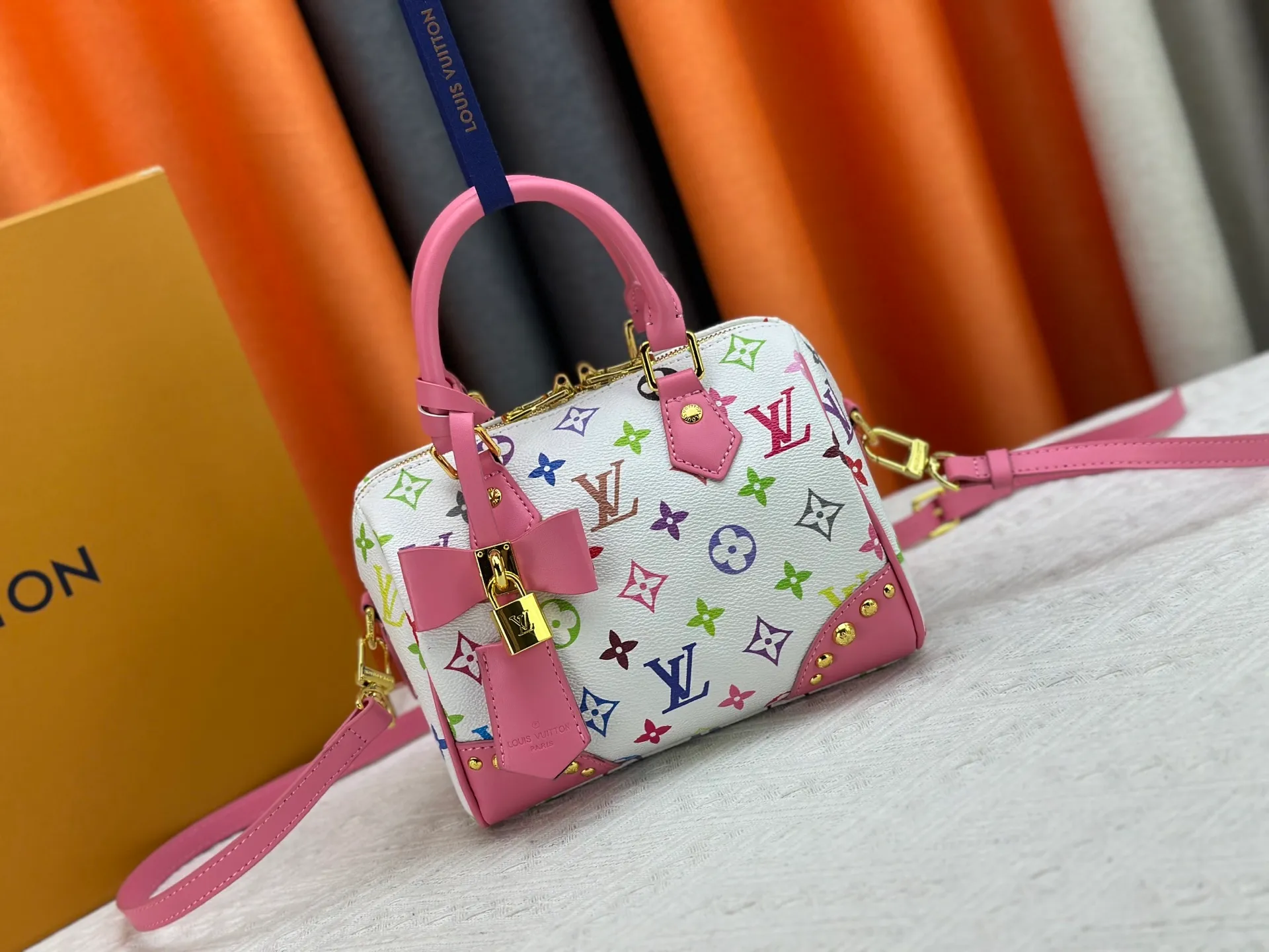 P260 upgraded original M58953 M46234 M46222 Speedy Bandoulière 20 handbag is made of soft coated canvas, and the full-length Monogram pattern is traced in colorful rainbow tones, highlighting the smart style of the Louis Vuitton x Murakami reissue series. The Toron handle and detachable shoulder strap are constructed of cow leather, the metal corners recall classic luggage elements, and the bow-shaped key bag and padlock add brand touches. Dimensions: 20.5 x 13.5 x 12.0 cm (length x height x width)