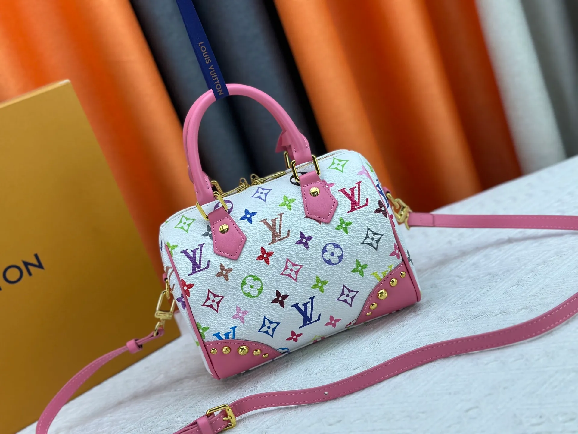 P260 upgraded original M58953 M46234 M46222 Speedy Bandoulière 20 handbag is made of soft coated canvas, and the full-length Monogram pattern is traced in colorful rainbow tones, highlighting the smart style of the Louis Vuitton x Murakami reissue series. The Toron handle and detachable shoulder strap are constructed of cow leather, the metal corners recall classic luggage elements, and the bow-shaped key bag and padlock add brand touches. Dimensions: 20.5 x 13.5 x 12.0 cm (length x height x width)