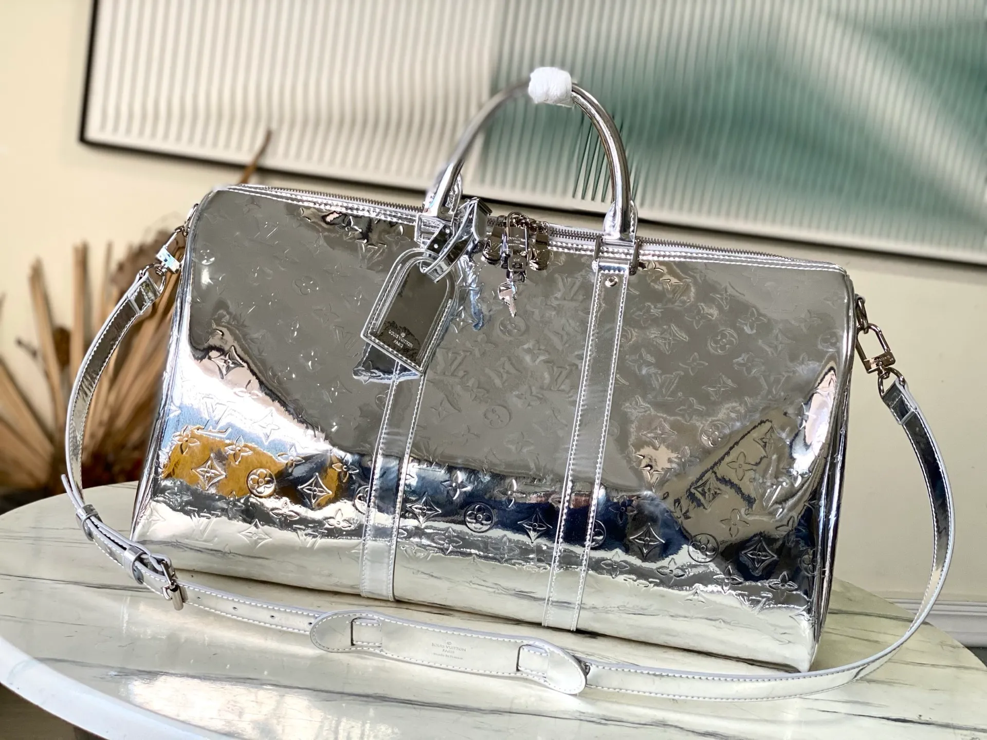 💰1560 (top layer leather) top original order M26766 silver This Keepall Bandouliere 45 travel bag uses Monogram Miroir canvas to convey a futuristic style, and then uses a mirror effect coating to upgrade its wear resistance. The hidden zipper pocket inside the mesh ensures safe storage of various items, and the top handle and detachable and adjustable shoulder strap allow for flexible carrying. Dimensions: 45 × 27 × 20 cm